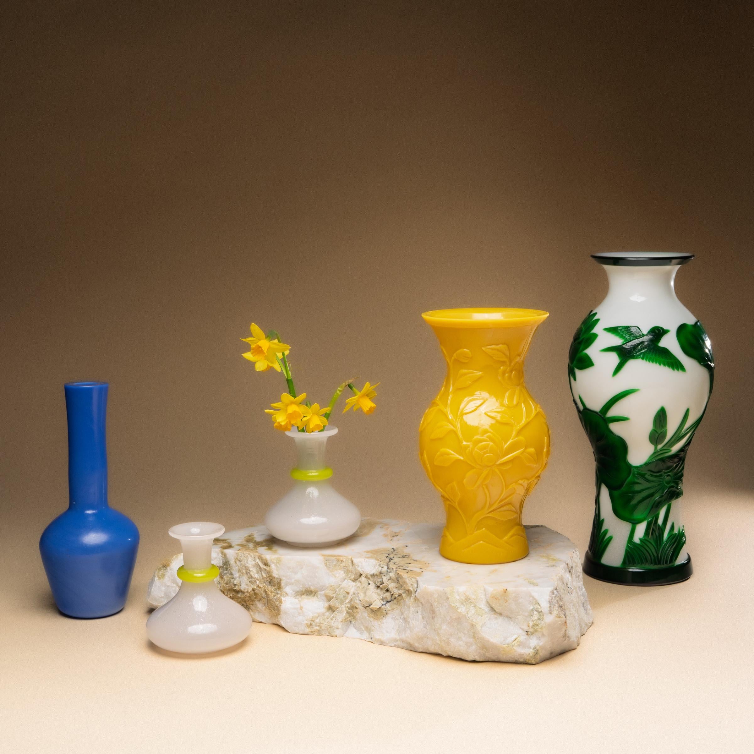 This petite pair of bud vases dates to the early 20th century and are elegantly shaped of white opaline glass with yellow accents. Shimmering with subtle crazing and iridescence, the art glass forms have sinuous silhouettes with wide bases, narrow
