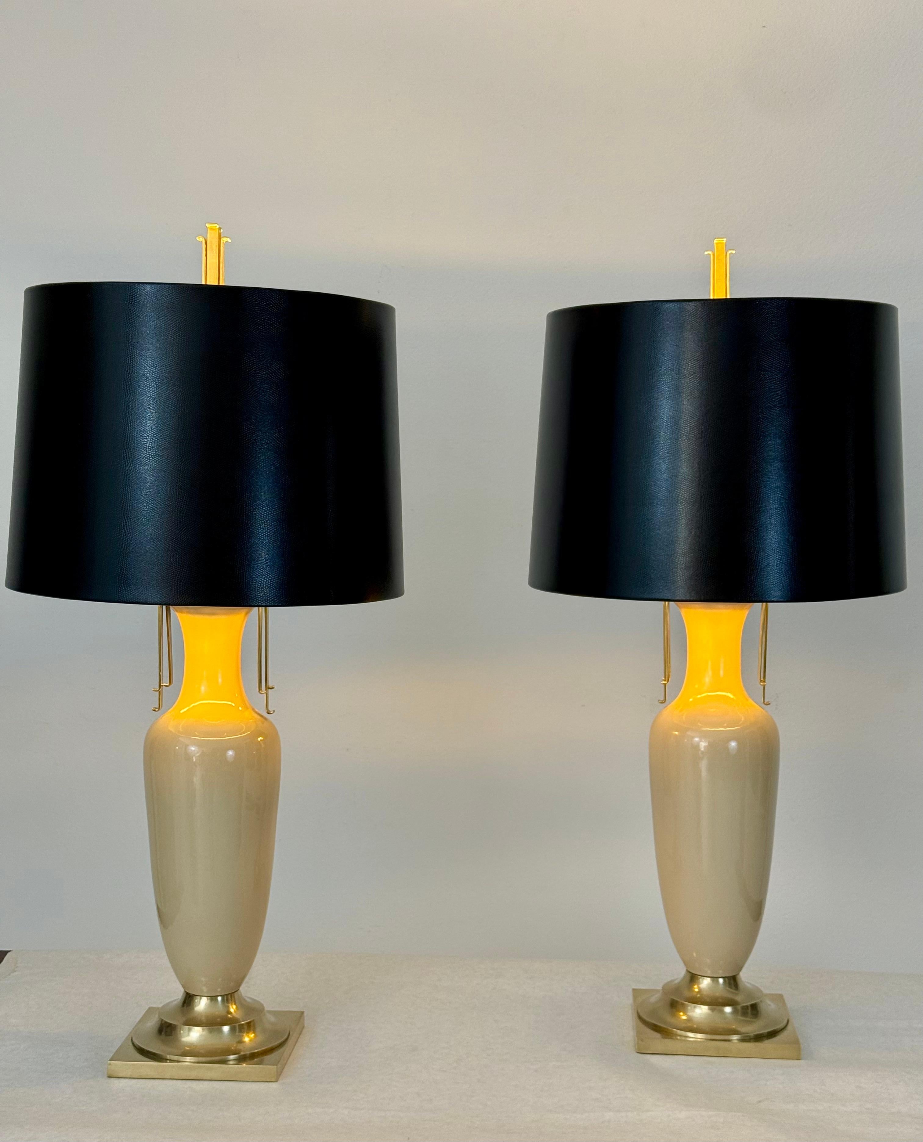 Ein Paar elegante und zeitlose urnenförmige Tischlampen von Chapman, datiert 1985. Diese Lampen zeichnen sich durch skulpturale Keramikkörper in einer warmen cremefarbenen Glasur aus, die durch raffinierte Details aus massivem Messing an Sockel und