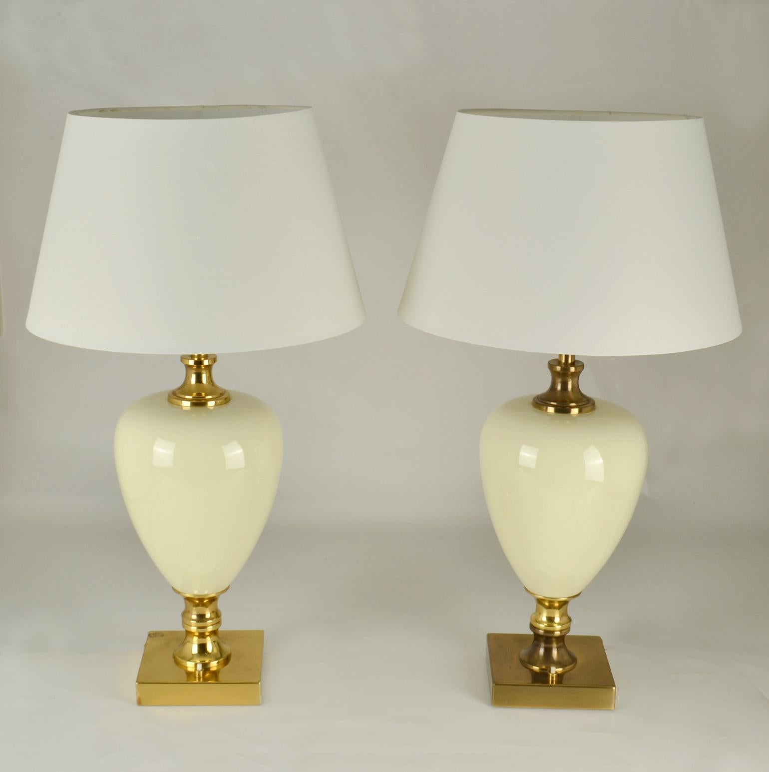 Pair of Italian Hollywood Regency table lamps with a body of cream shiny porcelain in the shape of an ostrich egg, encased by an elegant foot and top section in brass by Zonca, 1970's.
White new tapered shades are included.
Dimensions of the base