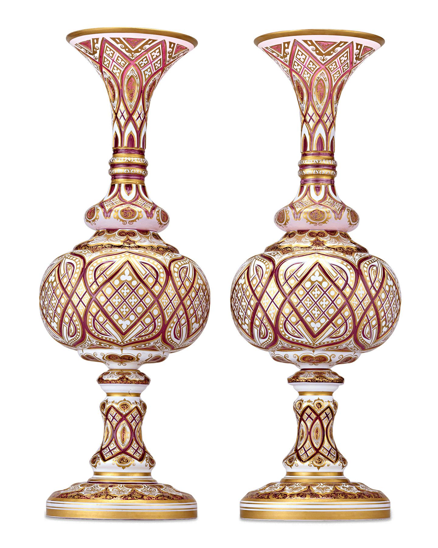 This resplendent pair of art glass vases exhibit the incredible detail and craftsmanship exemplary of Bohemian art glass. Rare crimson glass — the most coveted of Bohemian glass hues — mingles elegantly with white and gold in an intricately