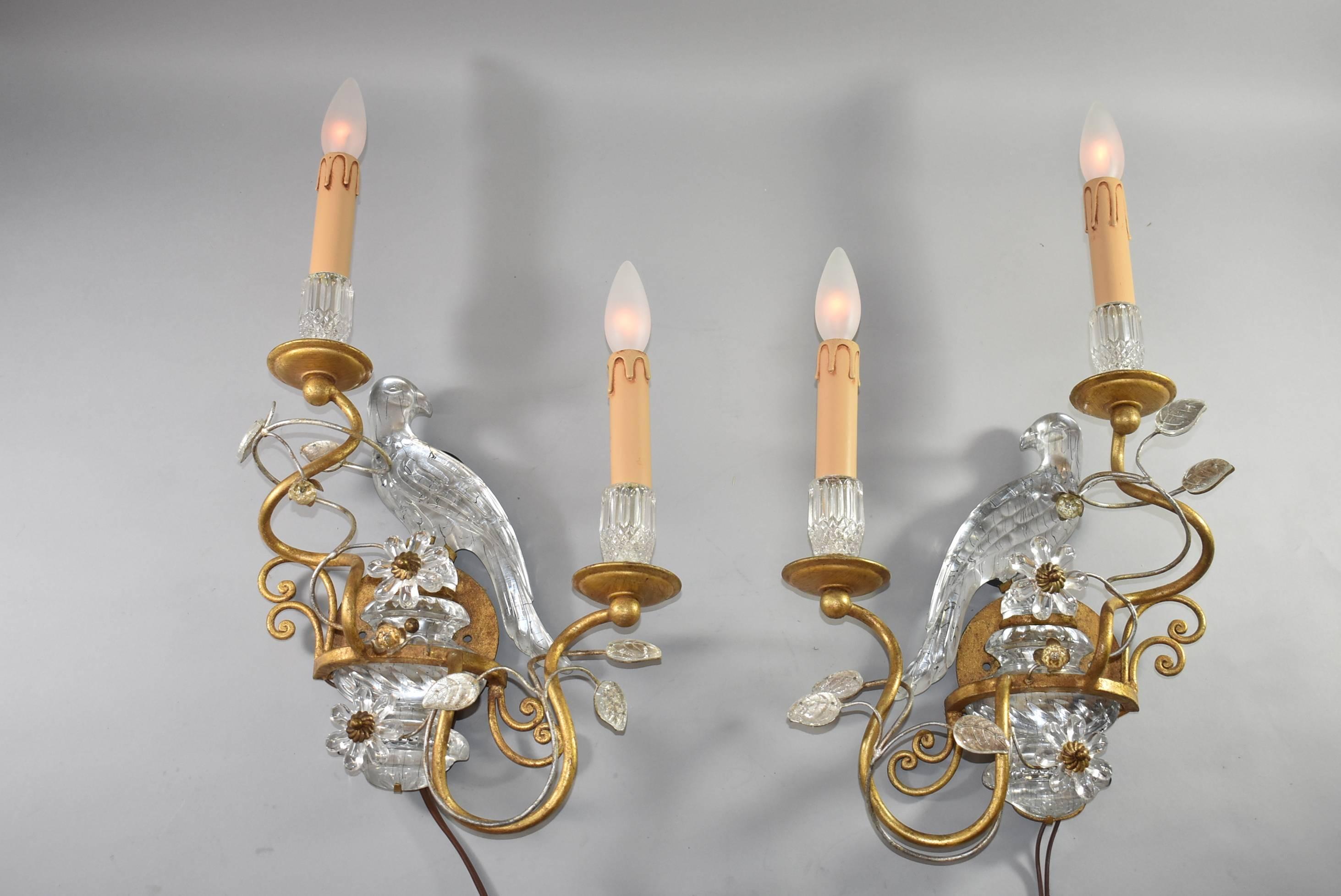 A stunning pair of antique wall sconces in the style of Maison Bagues of France. Each sconce is beautifully balanced with crystal leaves and a crystal urn with a stylized glass parrot perched upon it. Fluted crystal bobeches set off the crystal