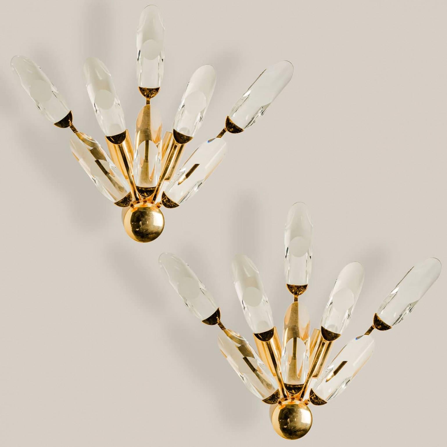 Pair of high-end gilded brass wall lights by Stilkronen, made in Italy, circa 1975.

Each fixture is featuring a half sunburst array of branches holding 8 clear crystals pieces.

The crystals refract light beautifully and are perfect for a soft,