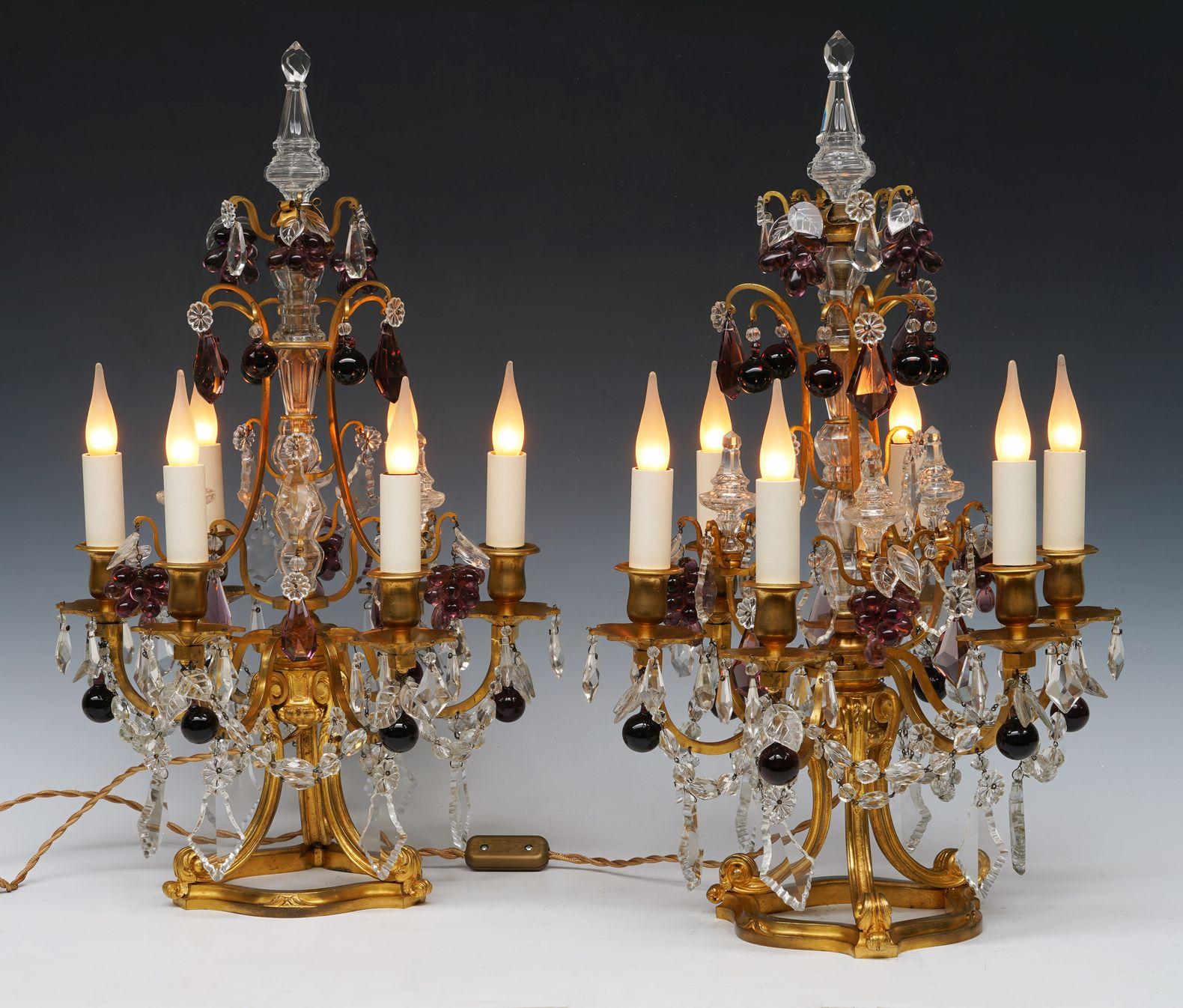 Beautiful pair of Louis XVI-inspired cage-shaped girandoles in gilded bronze, with a crystal baluster shaft and with six light-arms. The whole is nicely decorated with crystal pendants forming daggers, garlands, tassels and fruits. They rest on a