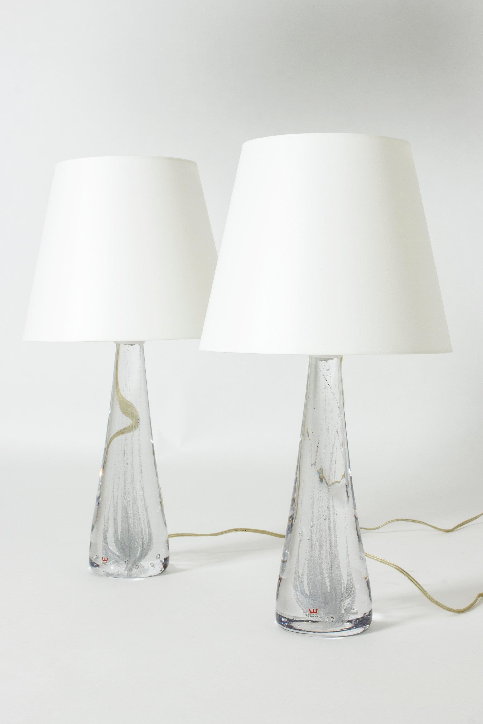 Pair of beautiful crystal glass table lamps by Vicke Lindstrand, organic conical in shape and with swirls of bubbles captured inside. Some of the bubbles are colored dark red, for a subtle contrast.
