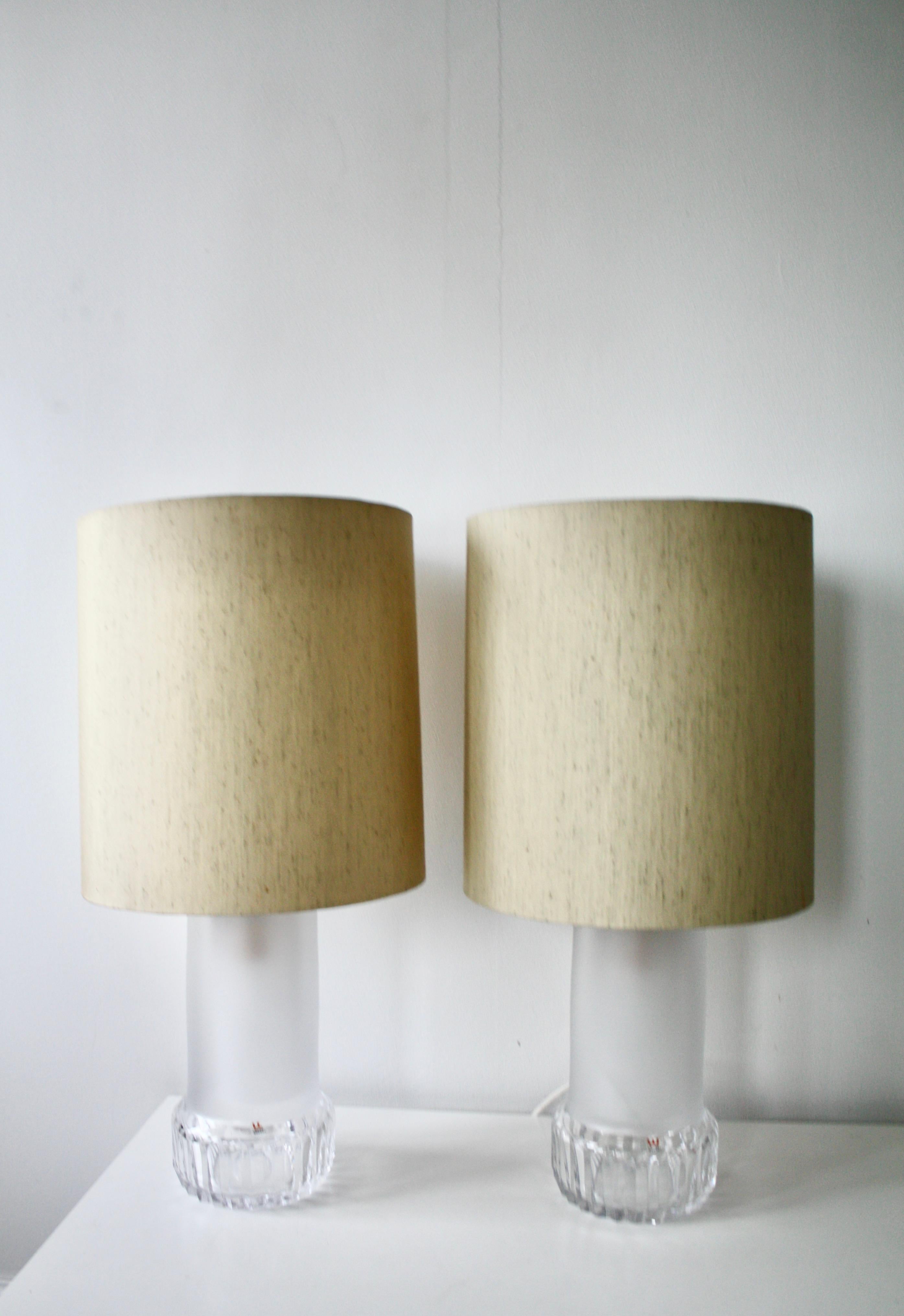 Elégante et intemporelle, cette paire de lampes de table en cristal a été conçue par Ove Sandberg pour Kosta Boda, l'une des plus prestigieuses verreries de Suède. Produites dans la seconde moitié du XXe siècle, ces lampes se caractérisent par un