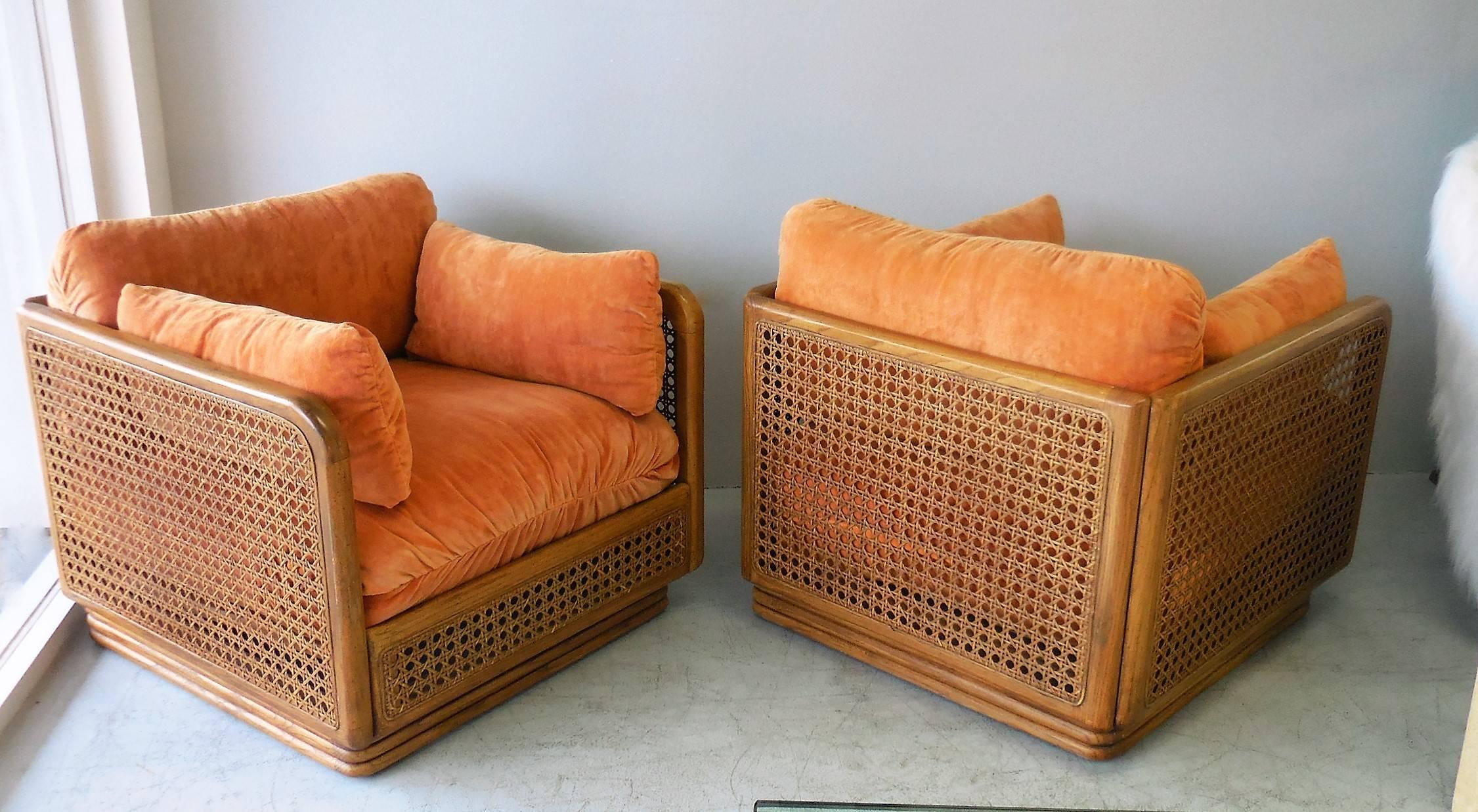 A handsome pair of wood and cane 1970s cube lounge chairs. Wood frames with very large open weaves. The cushions and pillows are removable. Clean simple design, tropical minimalism at its best.