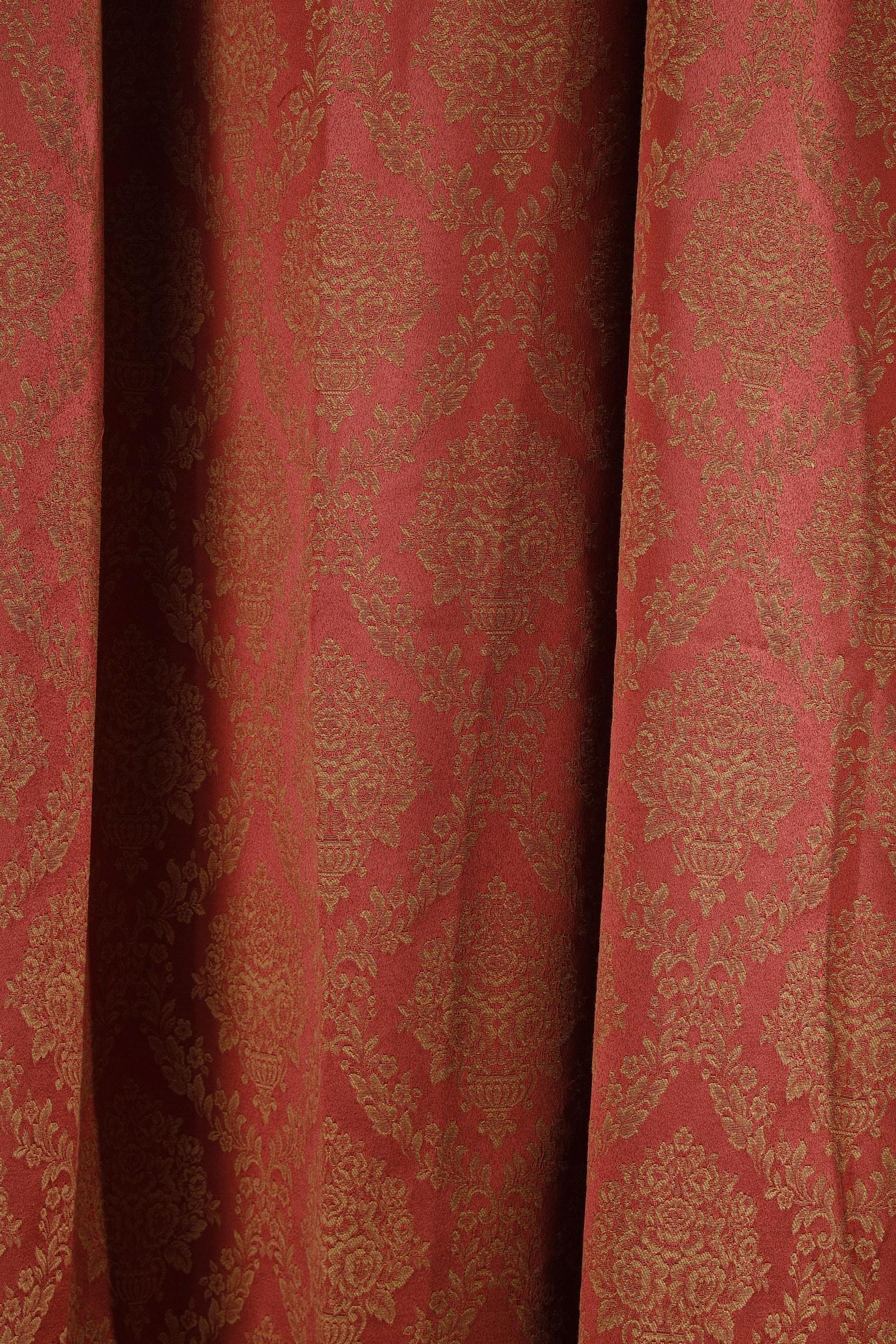 Pair of curtains and its valance surmounted by a gilded moulded wood banister. The curtains are made of red brocade fabric with decorations of vases overflowing with flowers in rhombus-shaped vegetal friezes. The valance with scalloped edge is made