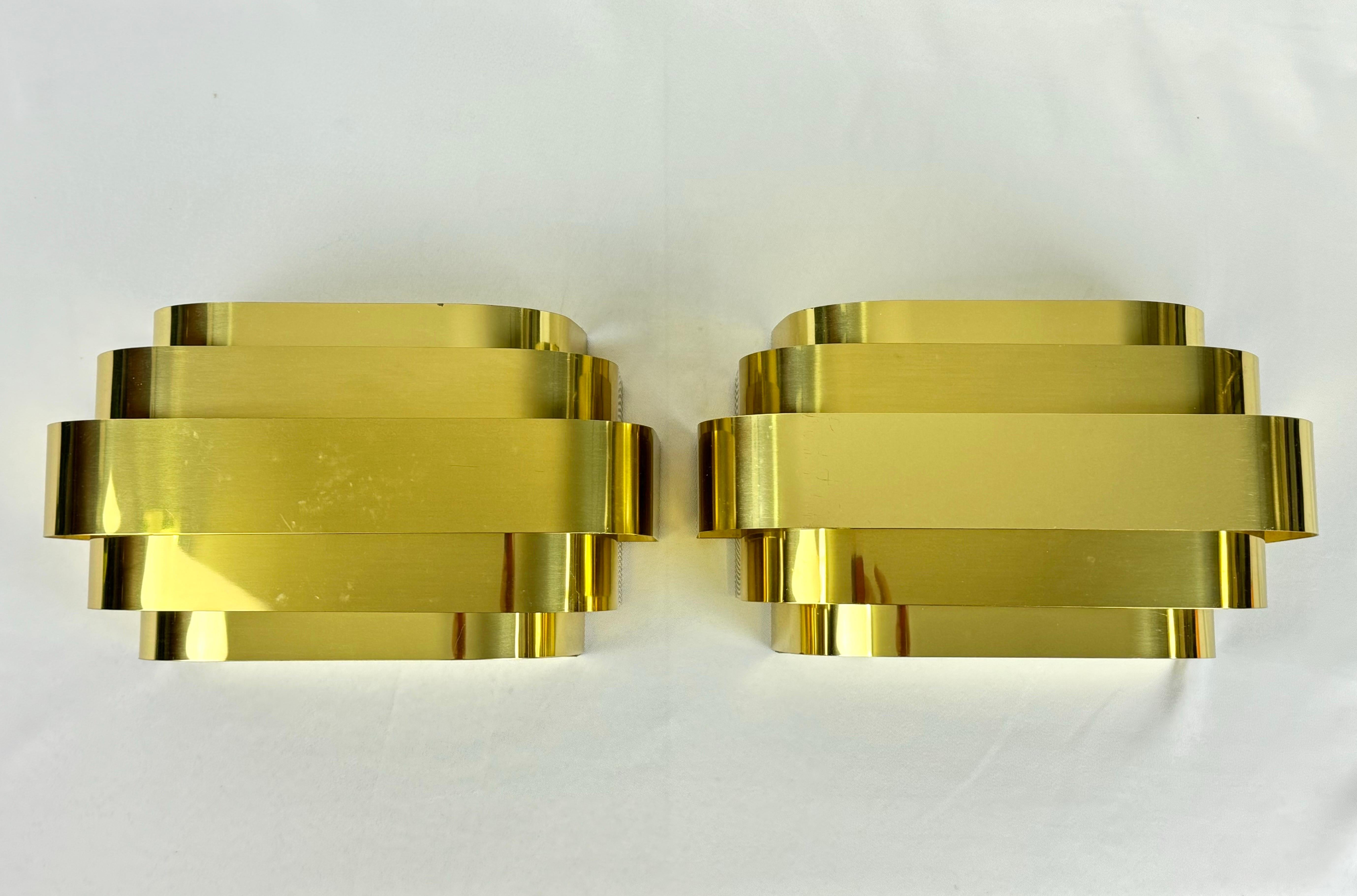 Pareja de apliques de latón estilo Curtis Jere de Lightolier. Forma de nube con 5 tiras frontales de latón para que se filtre la luz. Iluminación ambiental perfecta. El Art Decó se une a la modernidad de mediados de siglo. Tenemos varios juegos de