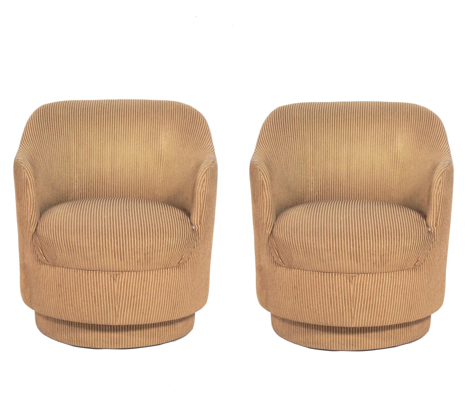 Pair of curvaceous swivel lounge chairs, in the manner of Karl Springer, American, circa 1960s. These chairs are currently being reupholstered and can be completed in your fabric. The price noted below INCLUDES reupholstery in your fabric.