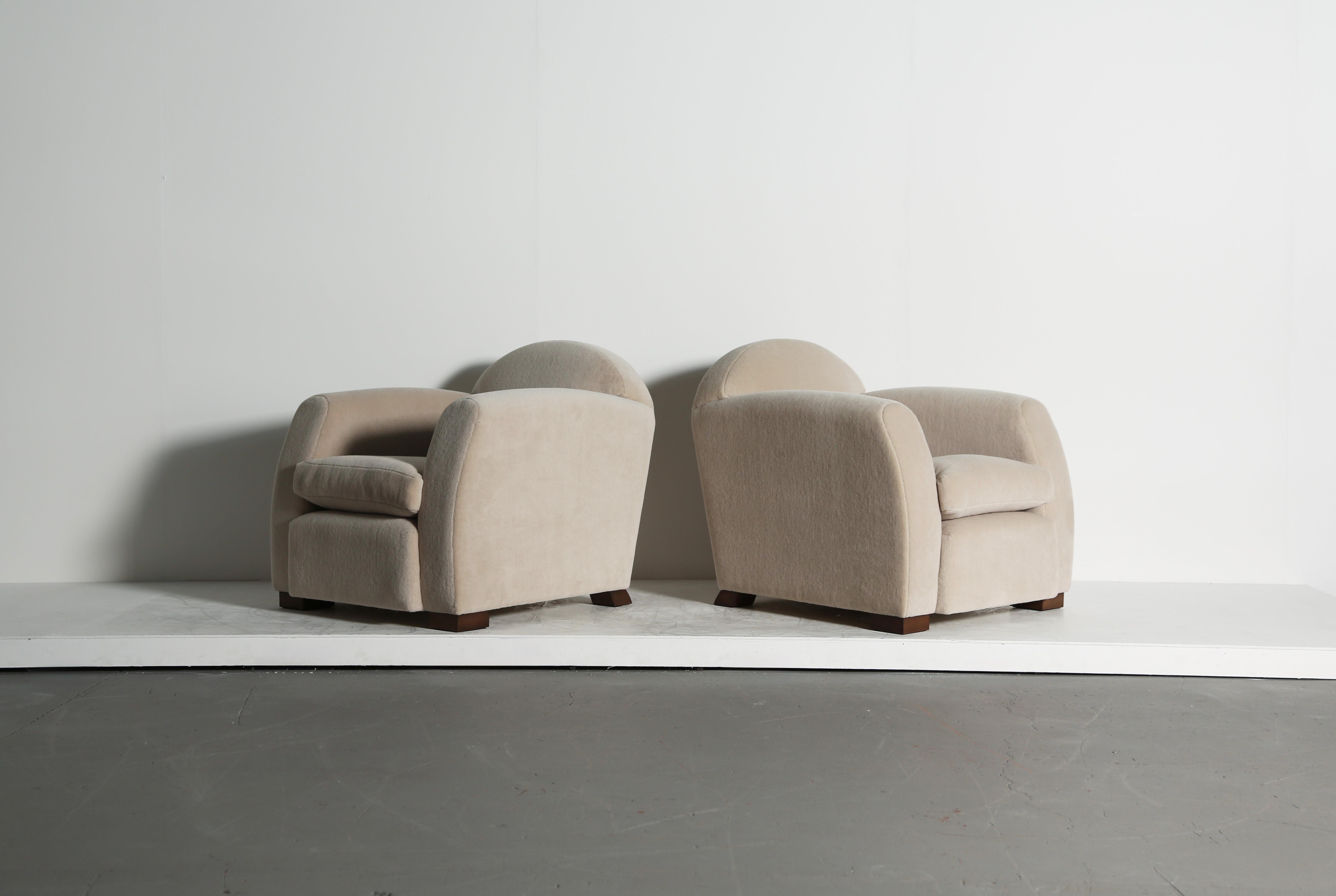 Una coppia elegante, lussuosa e confortevole di moderne poltrone con bracci curvi.  Struttura in Beeche, cuscini in piuma e sedili con molle.  Il rivestimento è stato realizzato con un pregiato tessuto di alpaca avorio, morbido e puro.   Realizzato