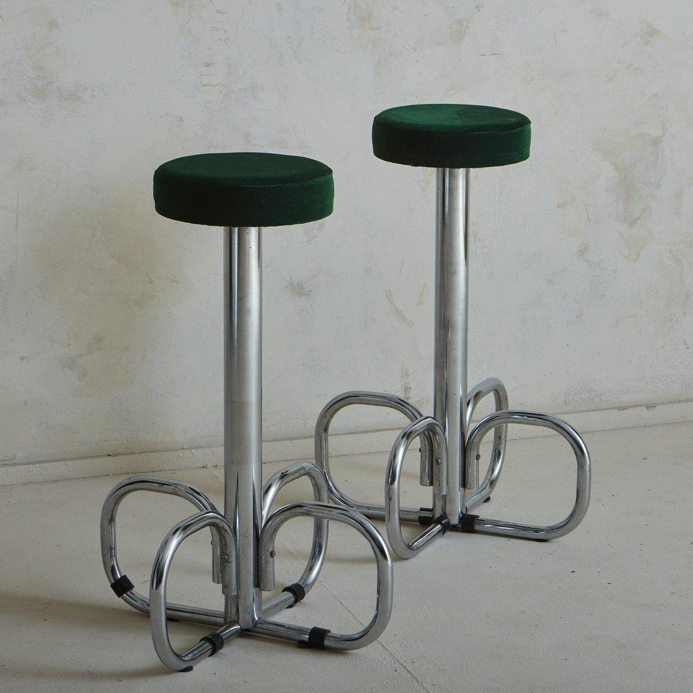 A pair of 1970s Italian bar stools featuring sculptural, curved chrome bases. These stools have circular seats, which retain their original green velvet upholstery. Sourced in Italy, 1970s.