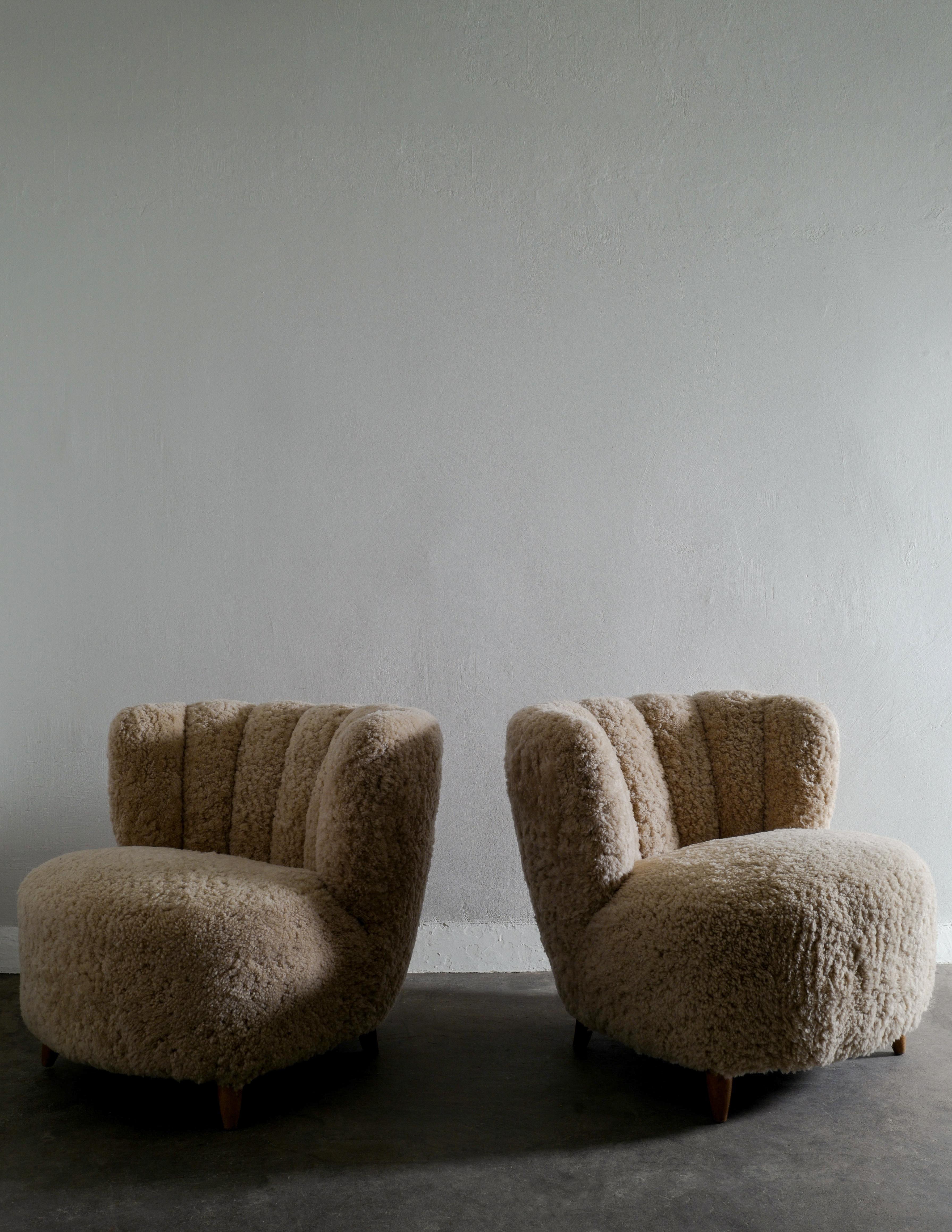 Rare pair of curved easy lounge chairs produced in Denmark in the 1940s and fully restored and upholstered with sheepskin by our professional. In great vintage condition with minimal signs from age and use.

Dimensions; H: 71 cm W: 80 cm D: 83 cm