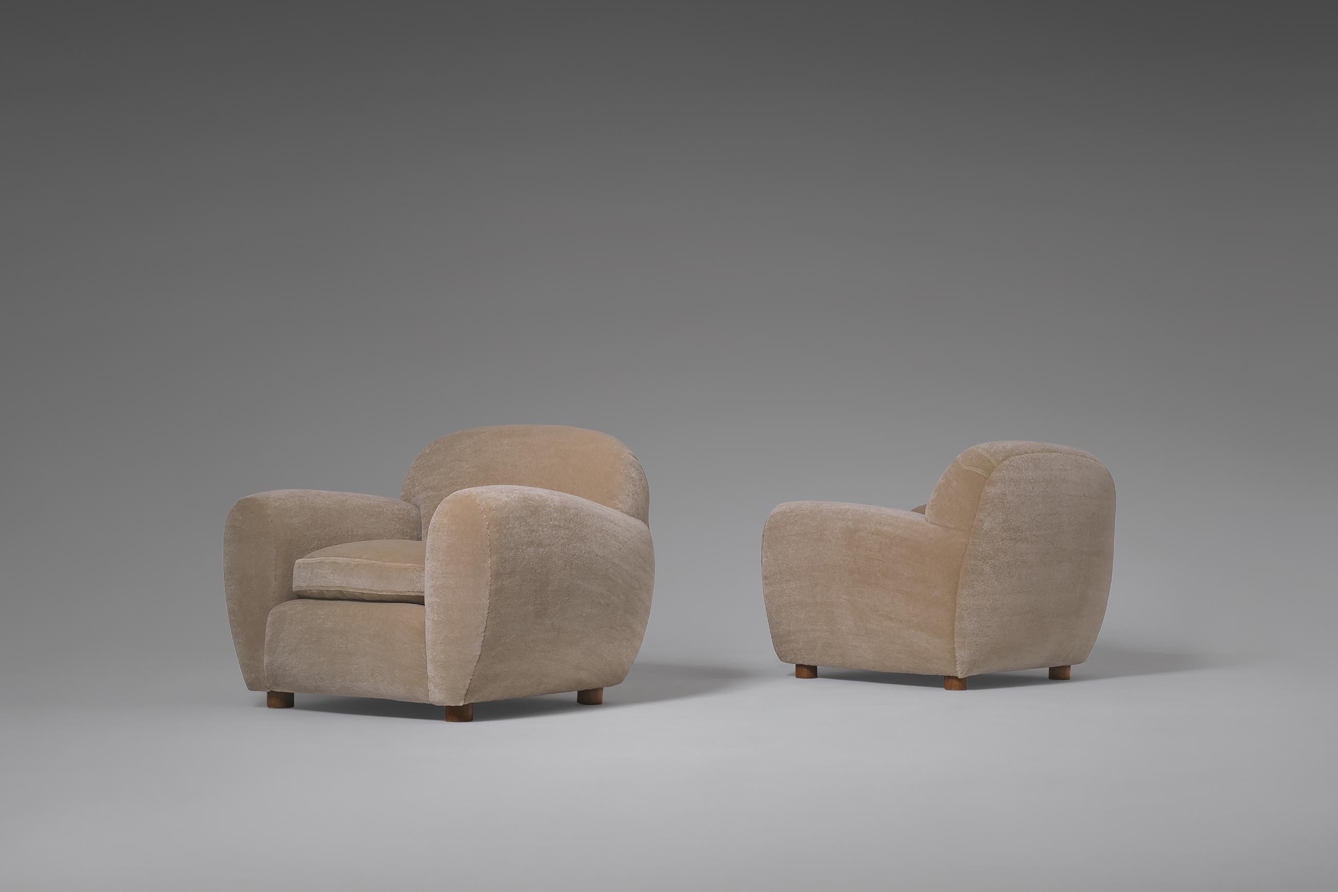 Stunning pair of lounge chairs in the style of Jean Royère, early 1950's. Impressive heavy curved shapes and line play with nice cilinder shaped Oak wooden legs. Unfortunately we haven't find the designer but these chairs are absolutely of top