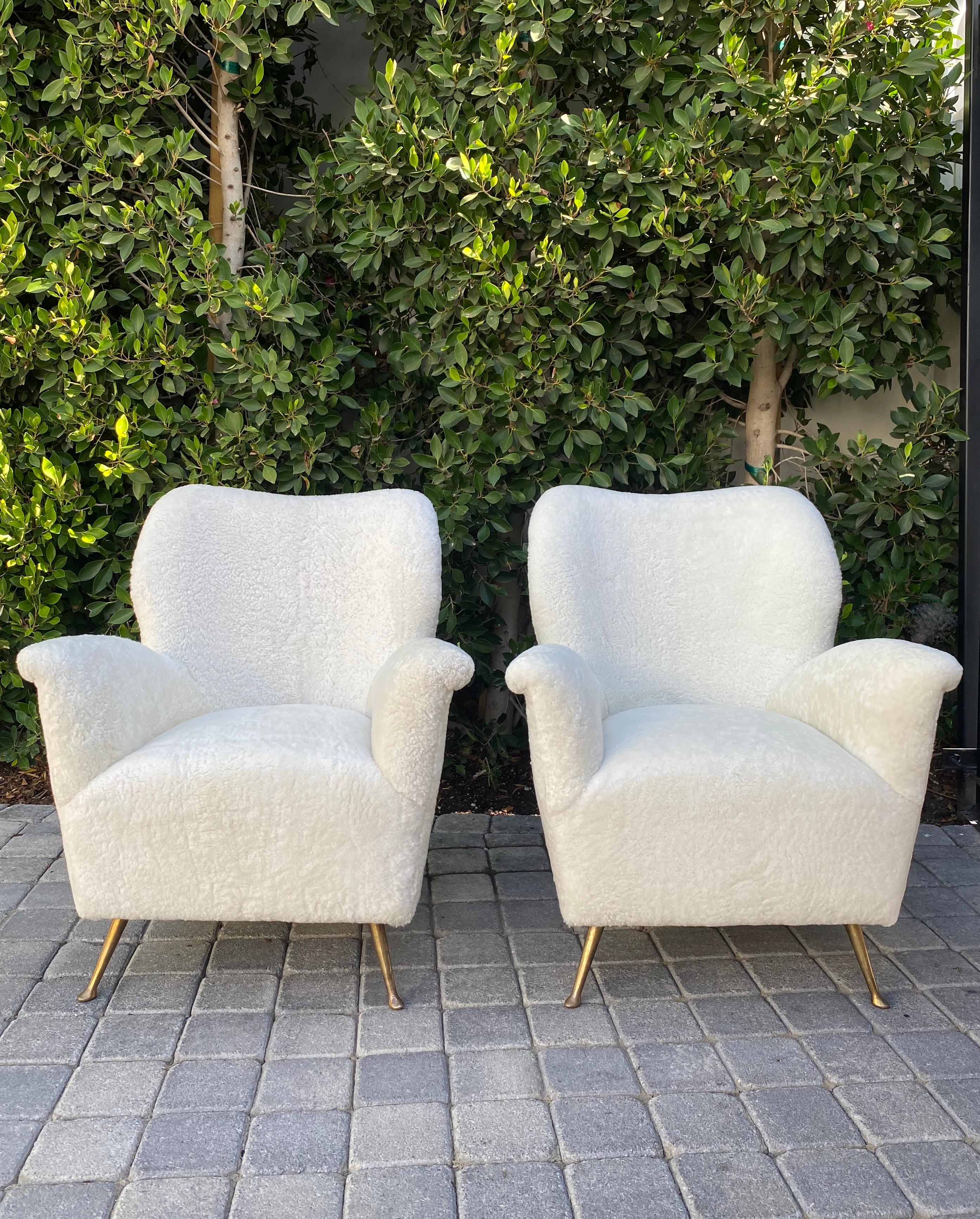 Pair of curved midcentury lounge chairs in white curly shearling reimagined from original Isa Bergamo form with solid brass legs.