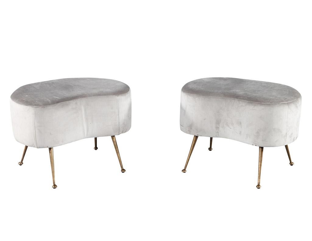 This pair of mid-century modern ottoman stools is truly a unique find. Crafted in Italy in the 1970's, these ottomans boast a chic curved design that is timeless in its appeal. Upholstered in a soft grey velvet, the stools are comfortable yet