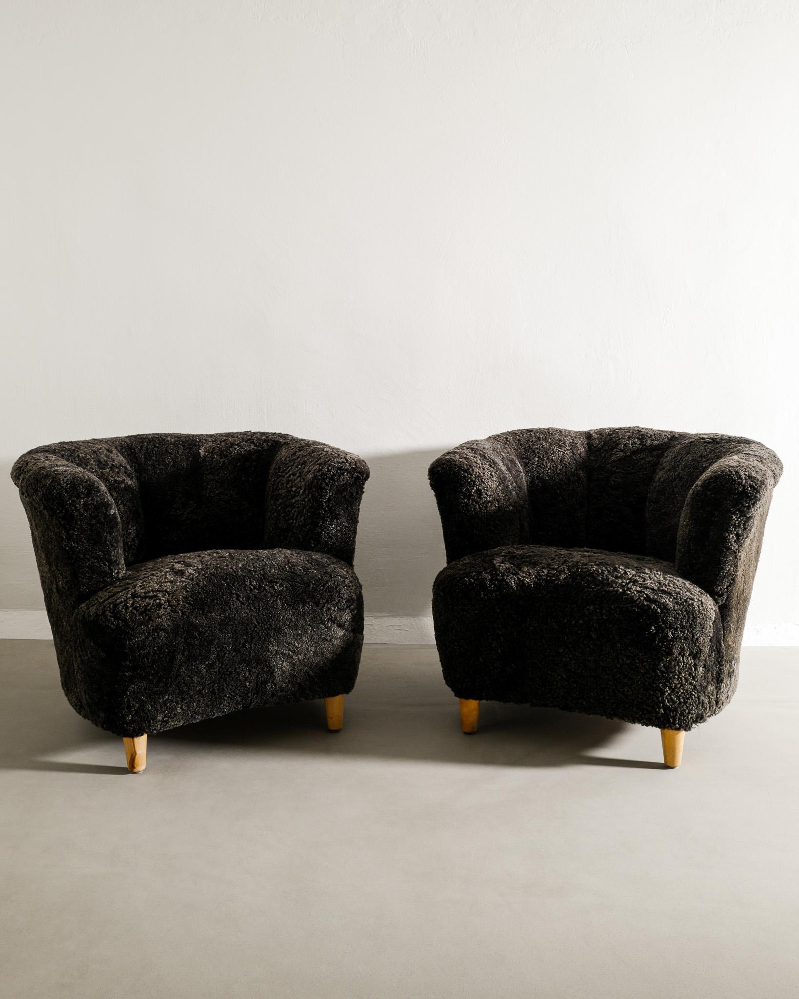 Rare pair of curved Swedish modern armchairs in style of Otto Schultz produced in Sweden, 1940s. In good condition and newly restored and upholstered in charcoal colored sheepskin. 

Dimensions: H: 68 cm / 27