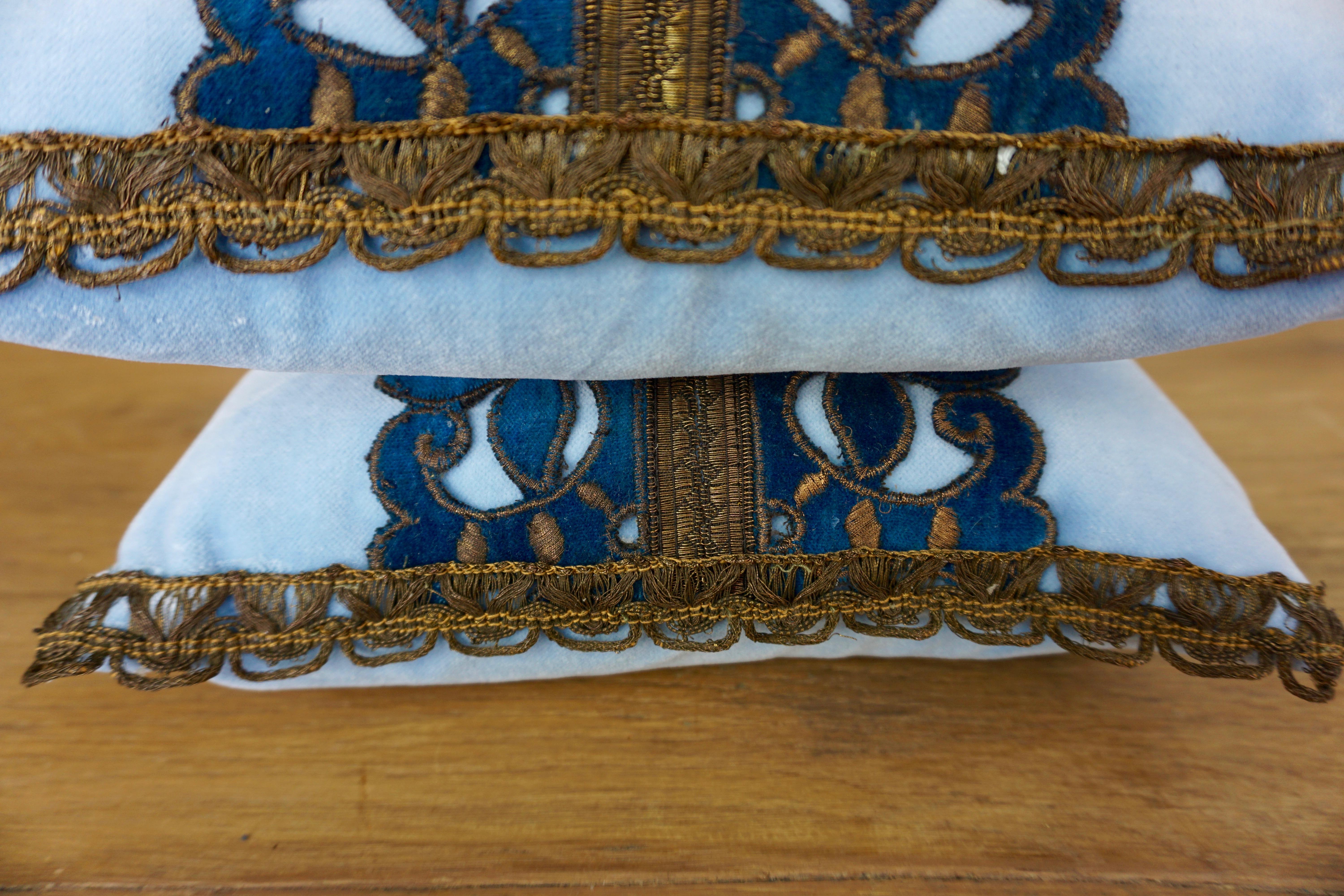 Pair of custom accent pillows designed by Melissa Levinson Antiques. The pillows are made with 19th century metallic and velvet appliqués on sky blue velvet fronts and backs. Down inserts, zipper closures.