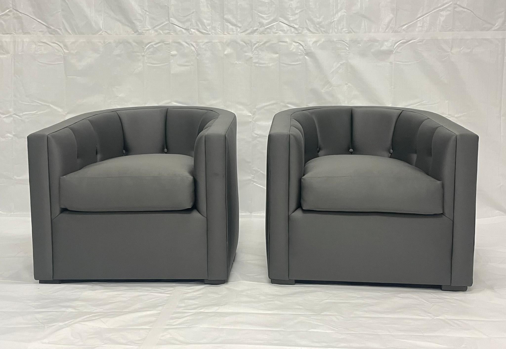 A refined pair of American-made transitional modern lounge chairs, custom-upholstered in charcoal gray performance fabric. The chairs feature a sleek barrel-back silhouette with channel-tufted interior panels and a squared exterior profile, merging