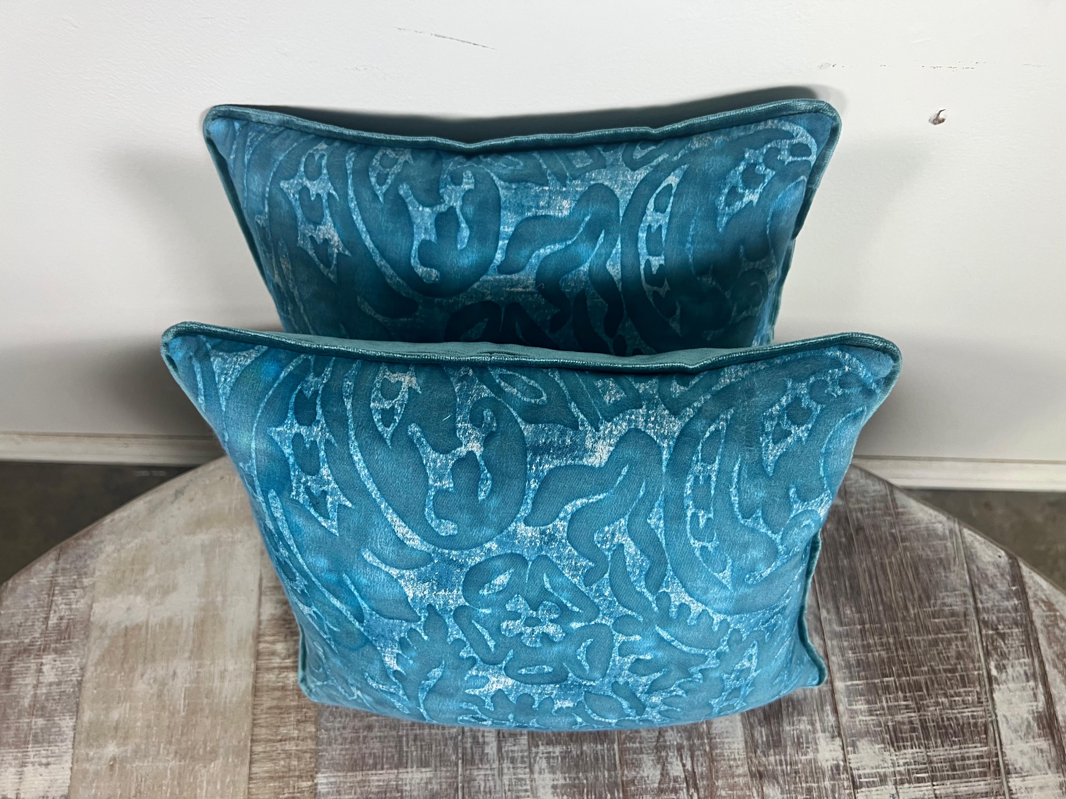 Coppia di cuscini in stile Fortuny, ciascuno rivestito di un accattivante blu acqua, un colore che evoca la profondità e il mistero delle acque oceaniche.  Questi cuscini sono impreziositi da una stampa floreale e di foglie in una tonalità di blu