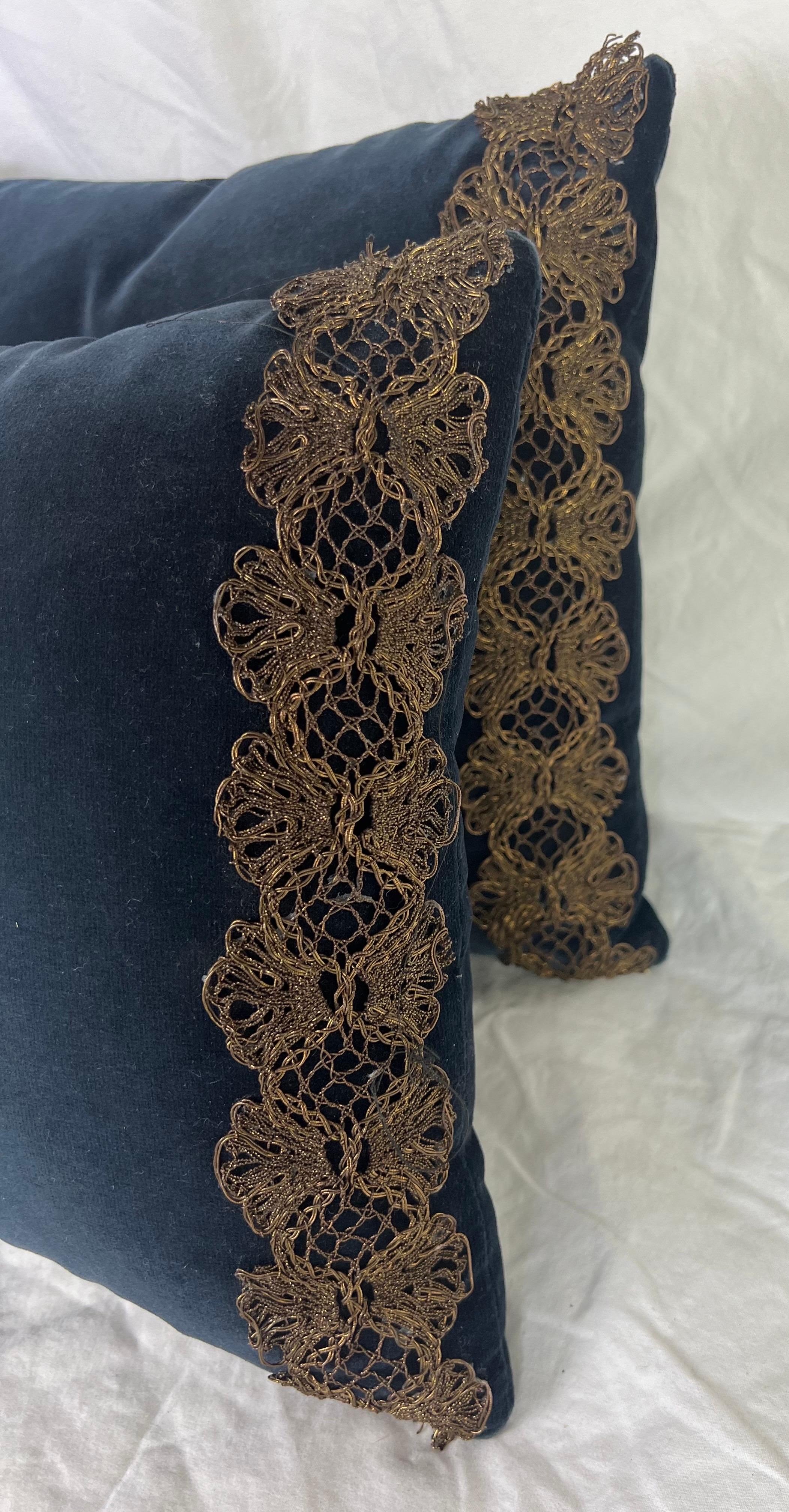 A pair of elegant navy blue velvet pillows with a central metallic & chenille appliques.  The edges of the pillows are adorned with an intricate gold metallic lace trim, which complements the central embroidery and adds a touch of vintage charm. 
