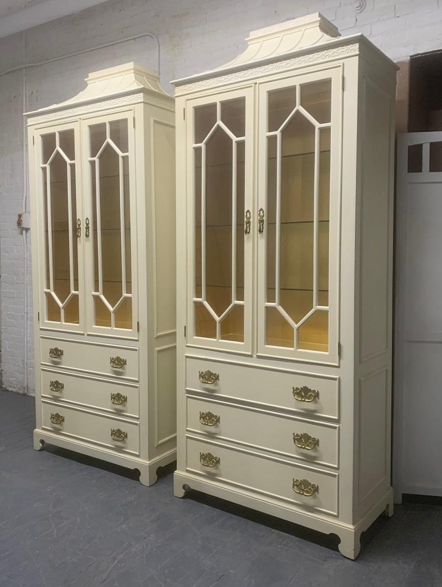 Pair of custom chinoiserie style cabinets. The cabinets can be lit, has a Pagoda style top, three glass removable shelves, and the original brass hardware. The inside is lined with gold wall paper. These cabinets were custom made for a loft