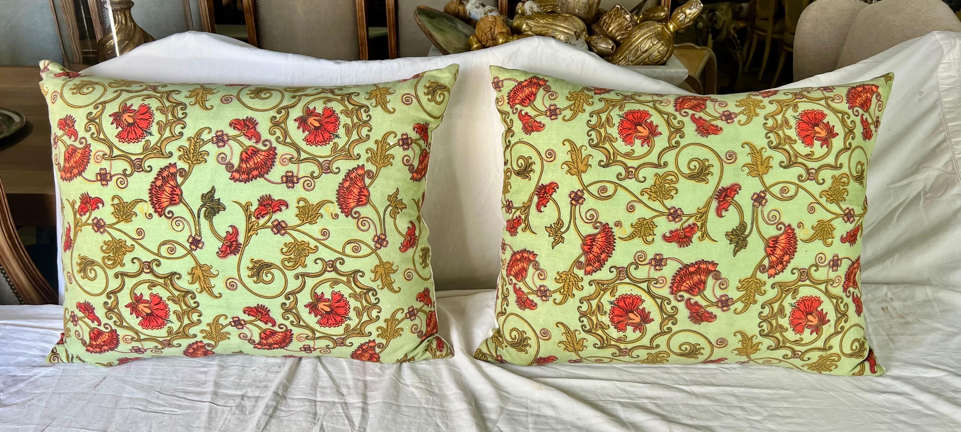 The pair of French Provincial custom pillows, showcasing swirling flowers in vibrant shades of green and orange, are paired with vintage white linen backs and down-filled inserts, adding a refreshing and classic touch to your decor.