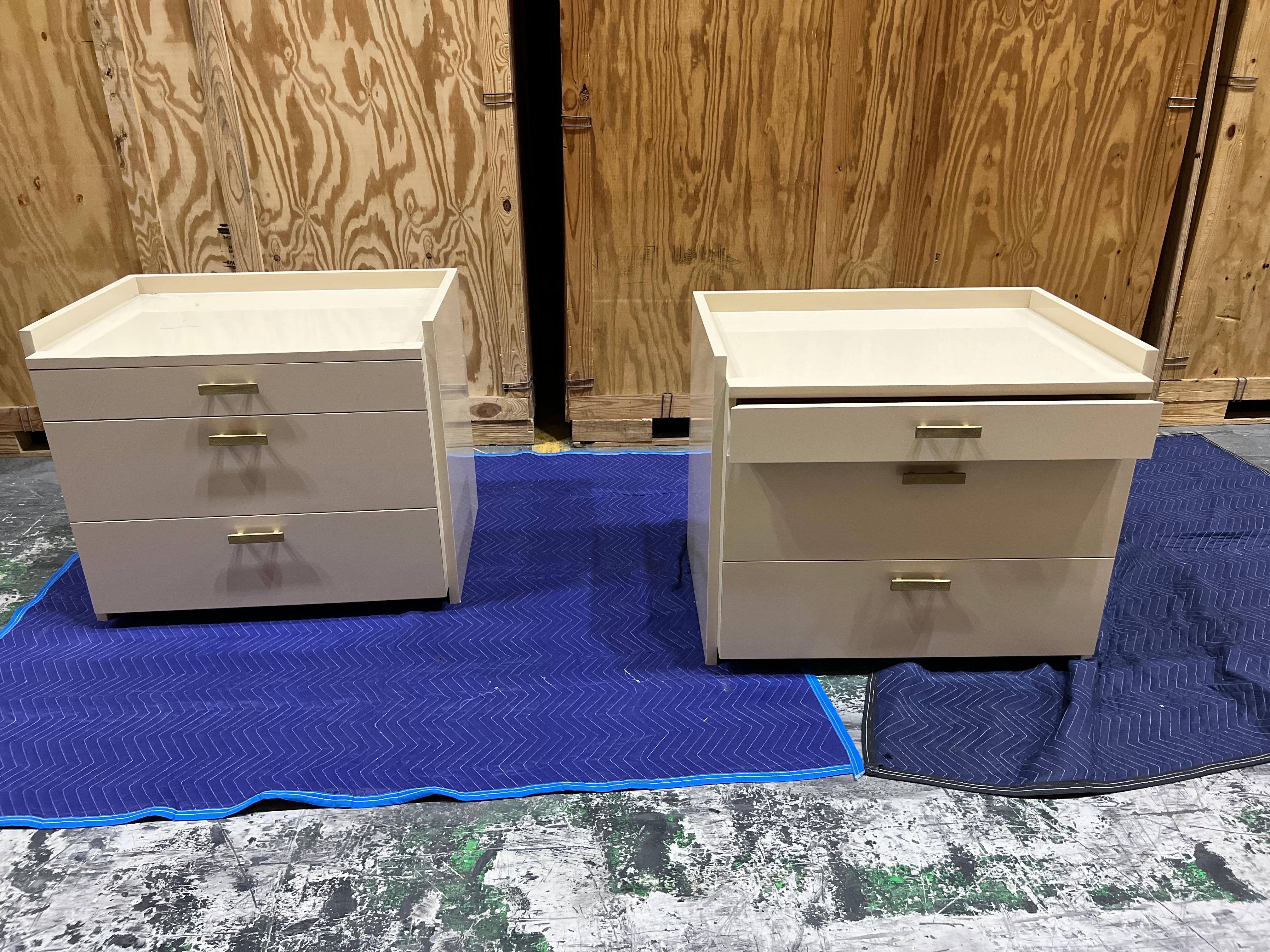 Pair of custom fabricated cream lacquered bedside tables.
Classic clean lined custom Bedside tables with three drawers and brass pulls.
Some wear to finish, slight flaking.
Measures: 36