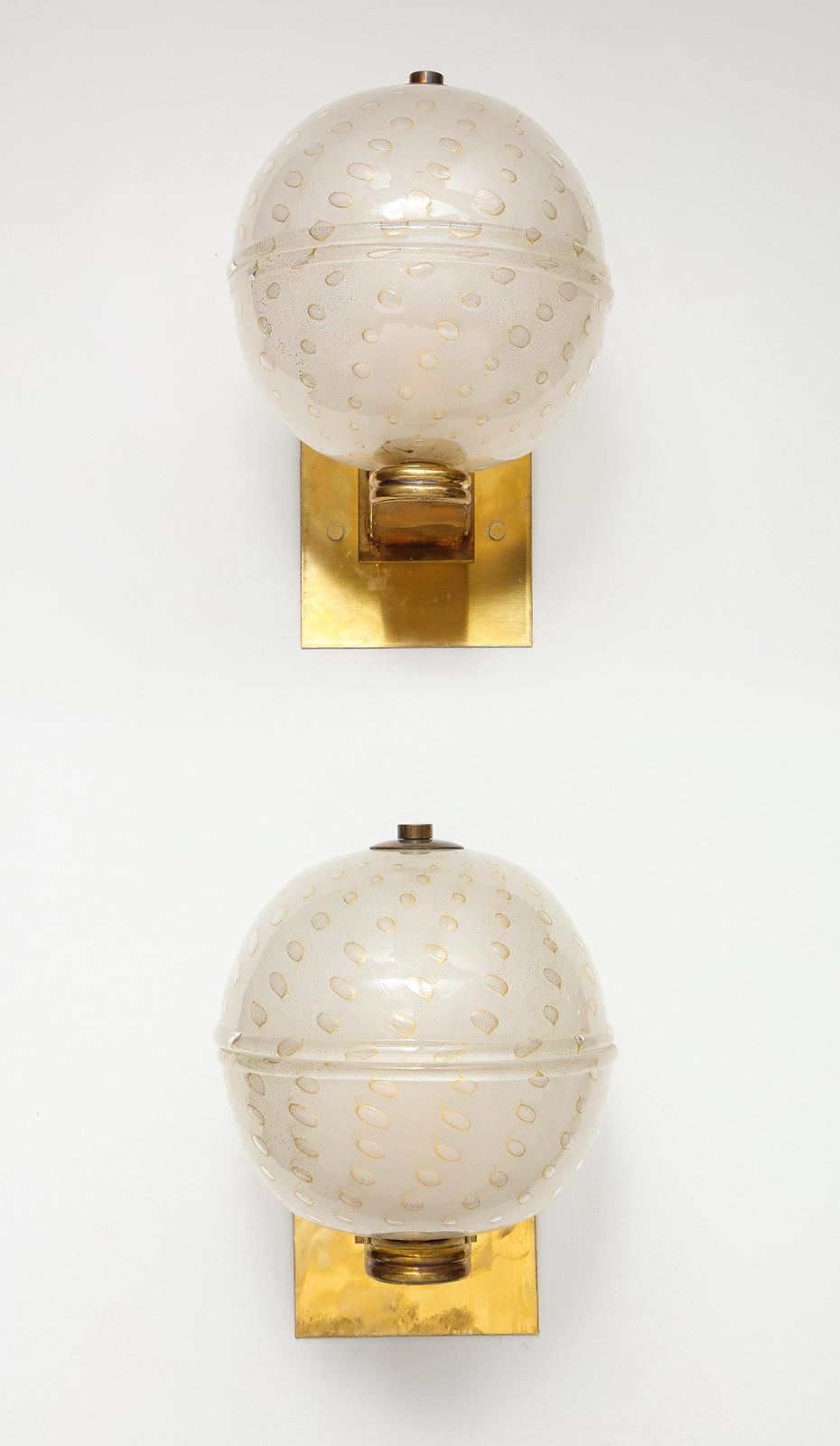 Pair of custom Murano glass sphere-shaped sconces with brass backplates. 
Italy, 21st century. 
The fixture is 9” H – including the backplate. Brass backplate is 4 ¼” x 4 ¼”.
7 ¾” projection from the wall. Globe is 6 ¾”W. Dimensions per each