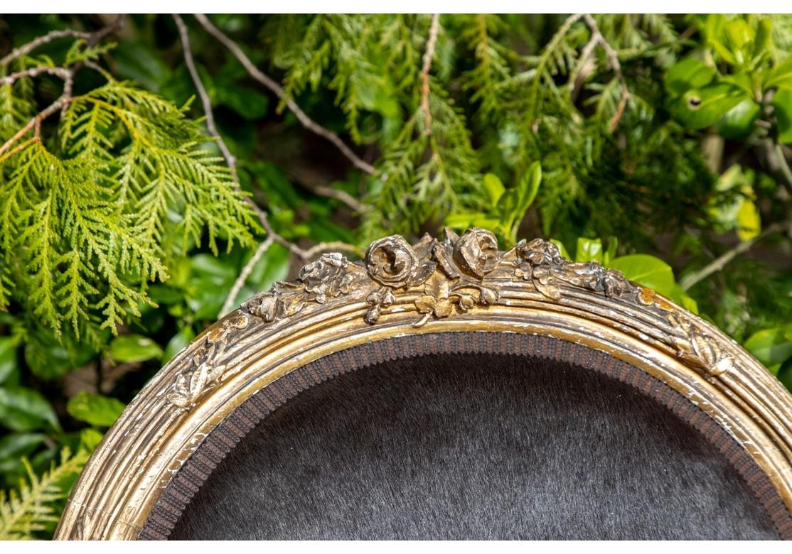 Classic 19th C. French carved and gilt fauteuils with elaborate crests with roses. Carved bound ribbed leafy frames and carved acanthus leaves on the arm ends. Raised on fluted cylindrical tapering legs with leafy feet. Upholstered in a deep