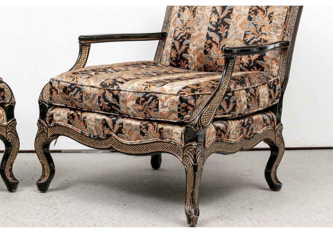 A pair of Stylish fauteuils in a custom finish in black lacquer with gilt feather pattern gilt bands on the frames. The crest rails and side supports with leafy details, the cabriole legs with acanthus leaves. With elegant sloping arm supports and