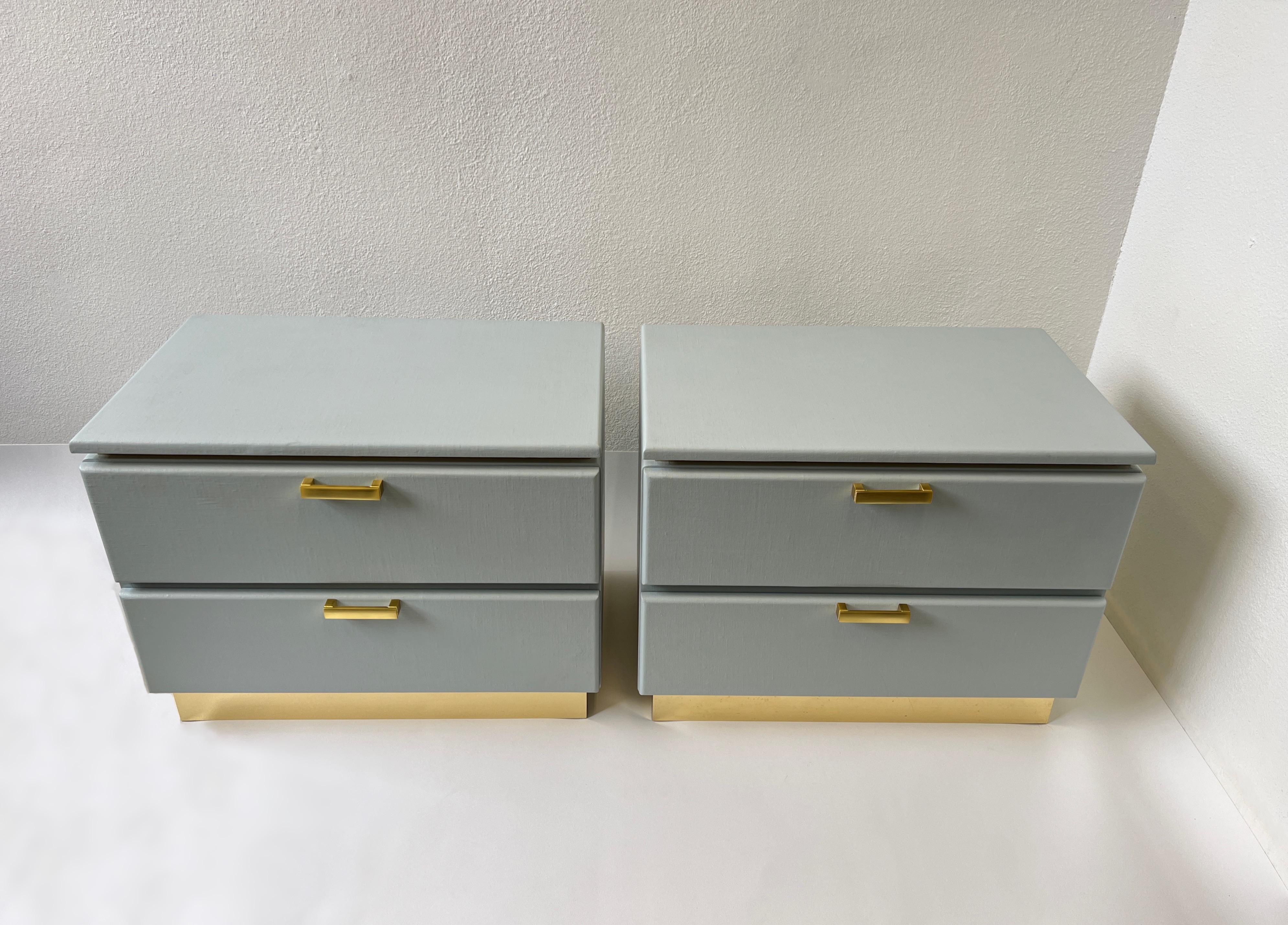 1980’s Pair of custom light bluish gray and brass lacquered nightstands for Steve Chase. 
Constructed of wood wrapped in lacquered linen, with brass details. 
In beautiful vintage condition, shows minor wear consistent with age. 
Measurements: