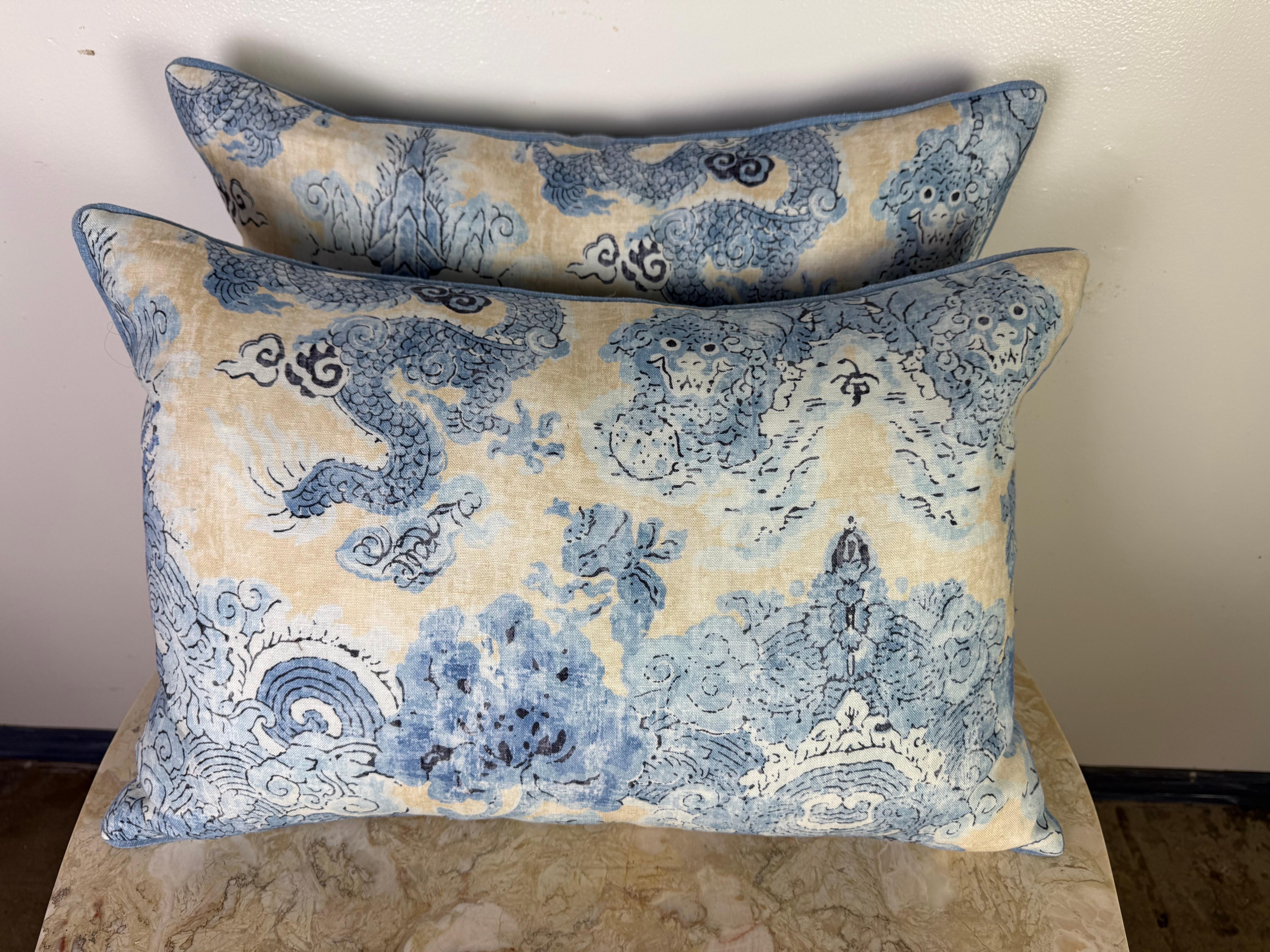Un'elegante coppia di cuscini personalizzati realizzati in lino stampato da Twigs, con un design pittorico ispirato alla cineseria. Il tessuto presenta morbide tonalità di azzurro, indaco e crema, con motivi dinamici di draghi e nuvole che