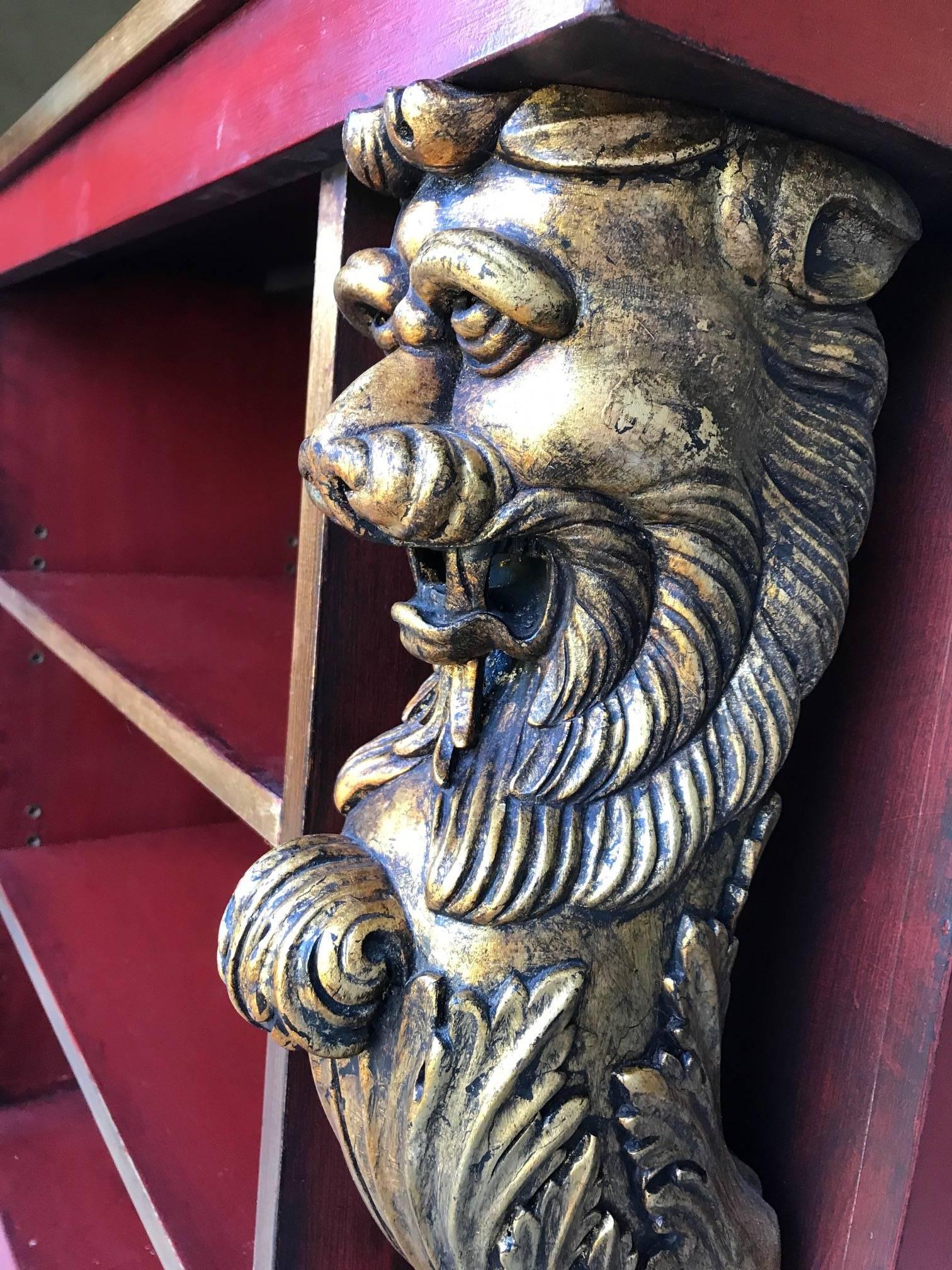 A pair of custom-made 20th century bookcases with carved gold gilt lions at each end. Commissioned for a large London residence. Hand-carved in red lacquer.