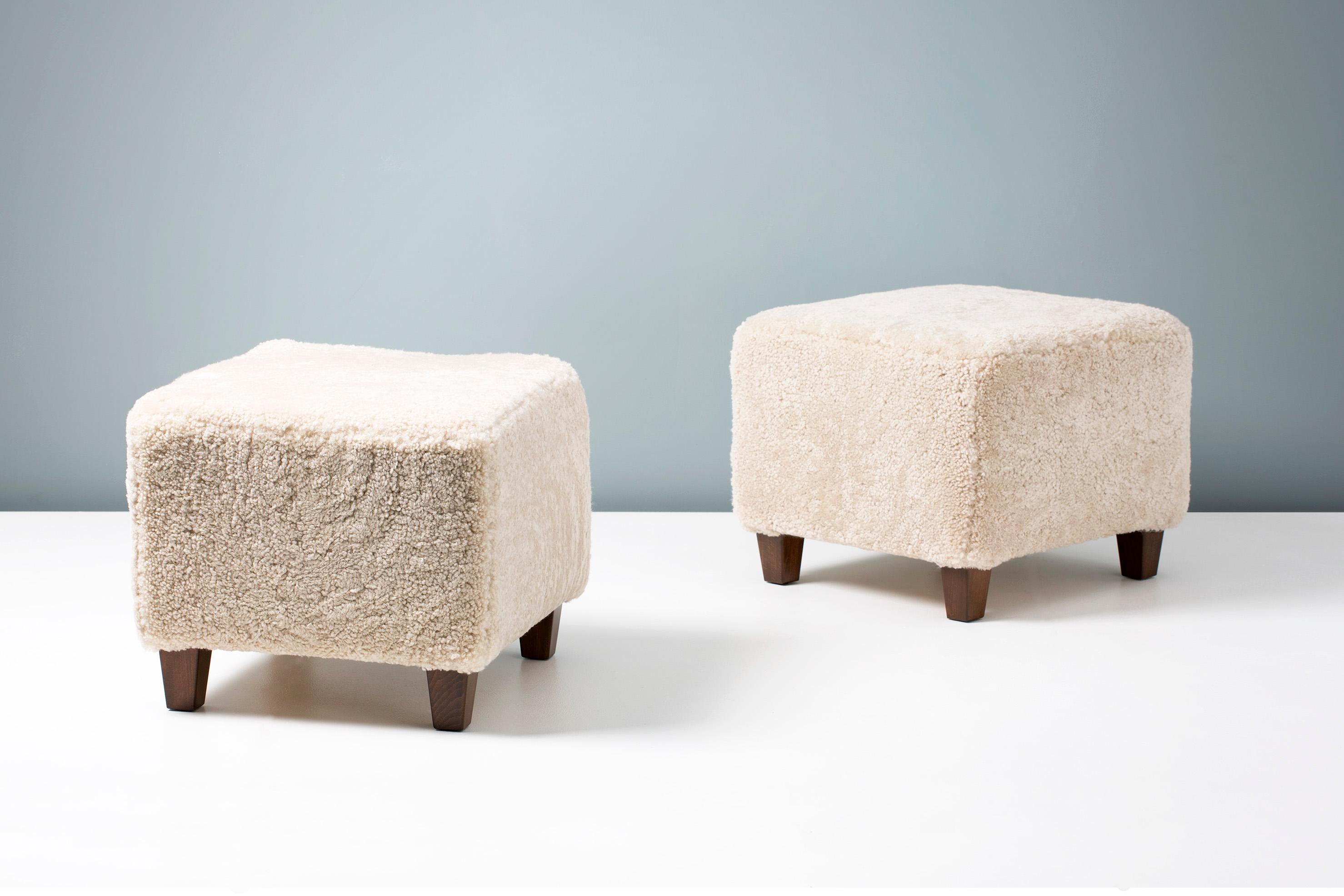 A pair of custom made shearling ottomans on hardwood base with stained beech legs. The foam body is covered in premium, tufted Australian shearling. 

These items are made to order in our London workshop, multiple pieces are available by request.