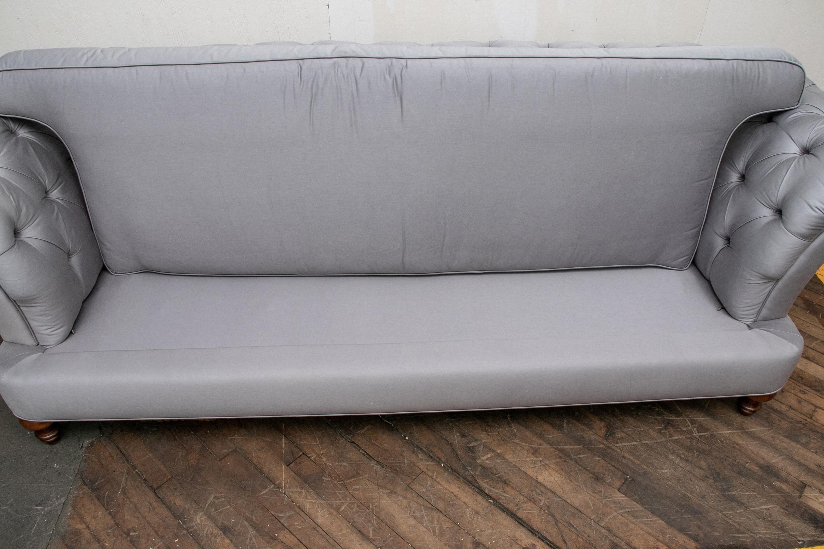 Each button tufted and upholstered in an ethereal silver cloud grey having rolled arms. The conforming single seat cushions partially down filled, the whole raised on mahogany turned bun feet. The pair are quite comfortable.

Condition: Overall