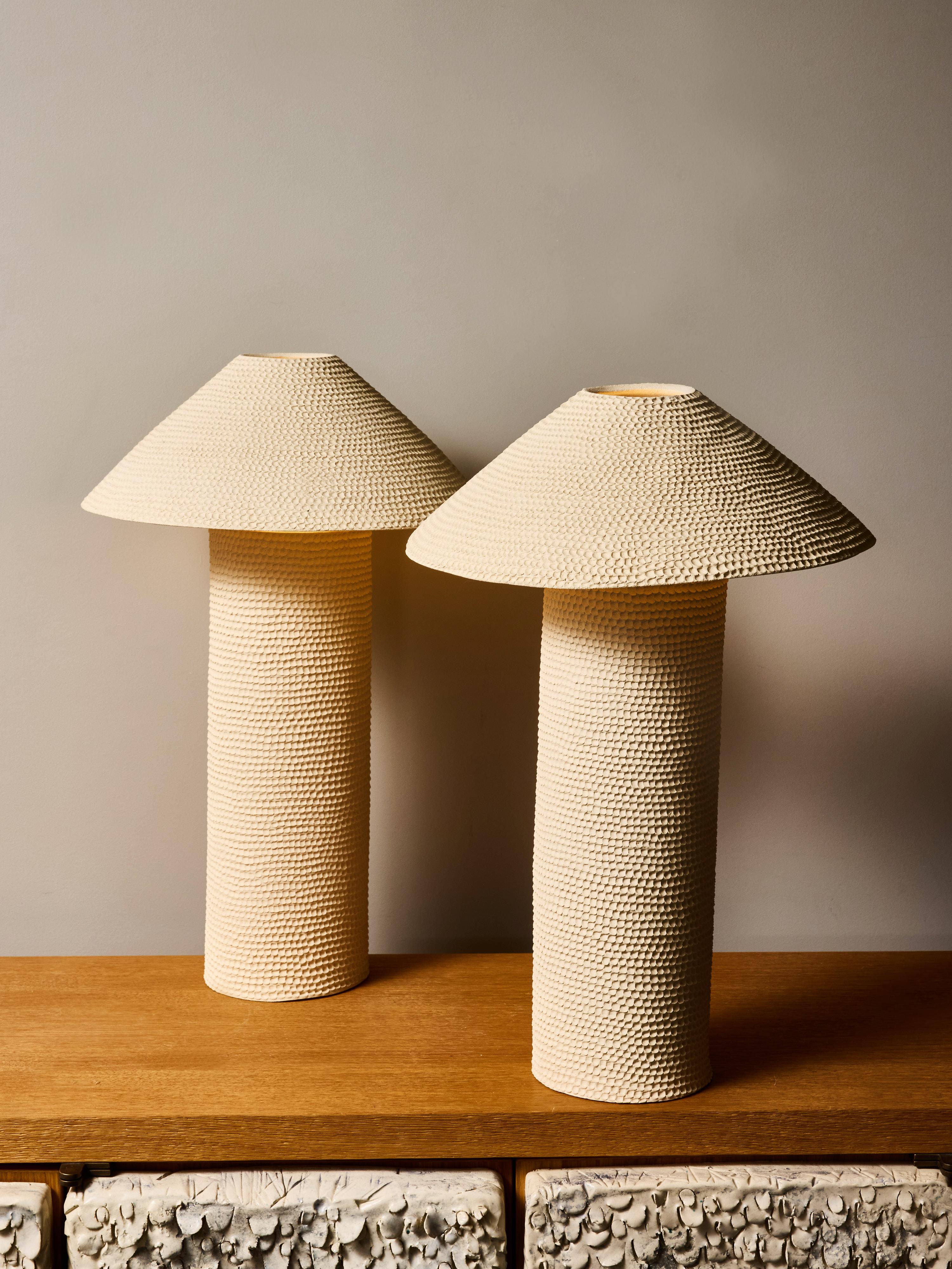 Dieses skulpturale Paar SMARA-Tischlampen der französischen Keramikkünstlerin Marie Fekroun zeigt ihre unverwechselbare Erforschung von Textur, Licht und raffinierter Handwerkskunst. Jede Leuchte wird in Handarbeit aus Steingut gefertigt und mit der
