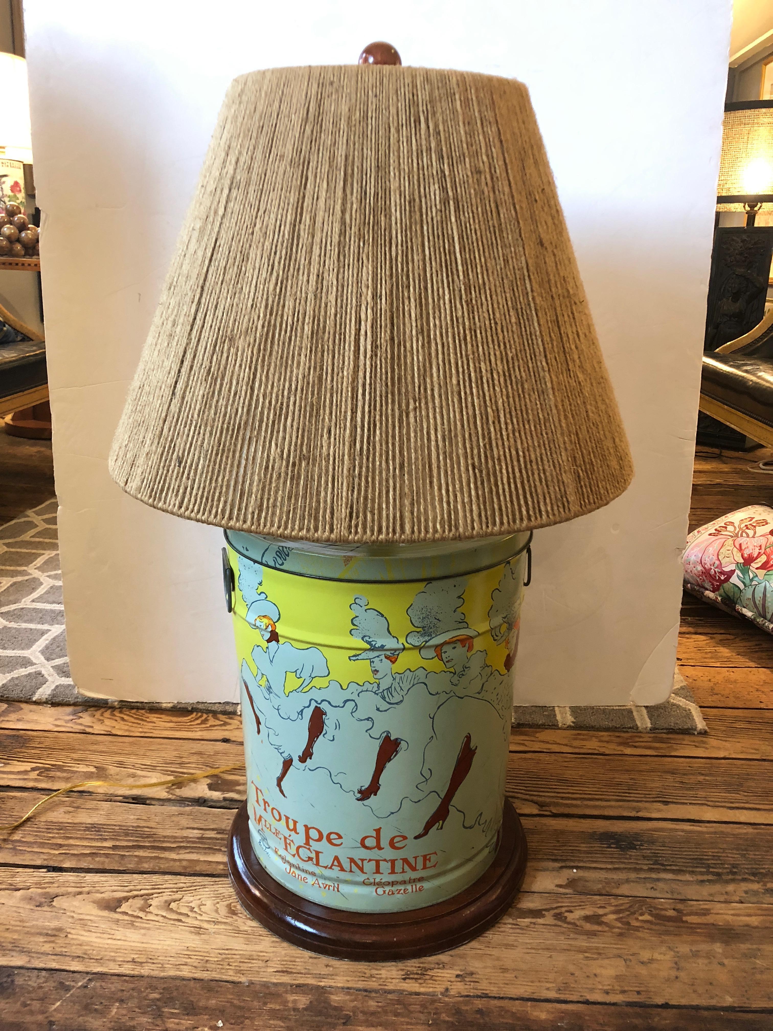 A wonderful pair of chunky tin canister lamps decorated in a pastel colored reproduction of the famous French artist Toulouse Lautrec. Originally vintage popcorn cans. Red headed dancers and graphic French words commingle in a palette of celadon