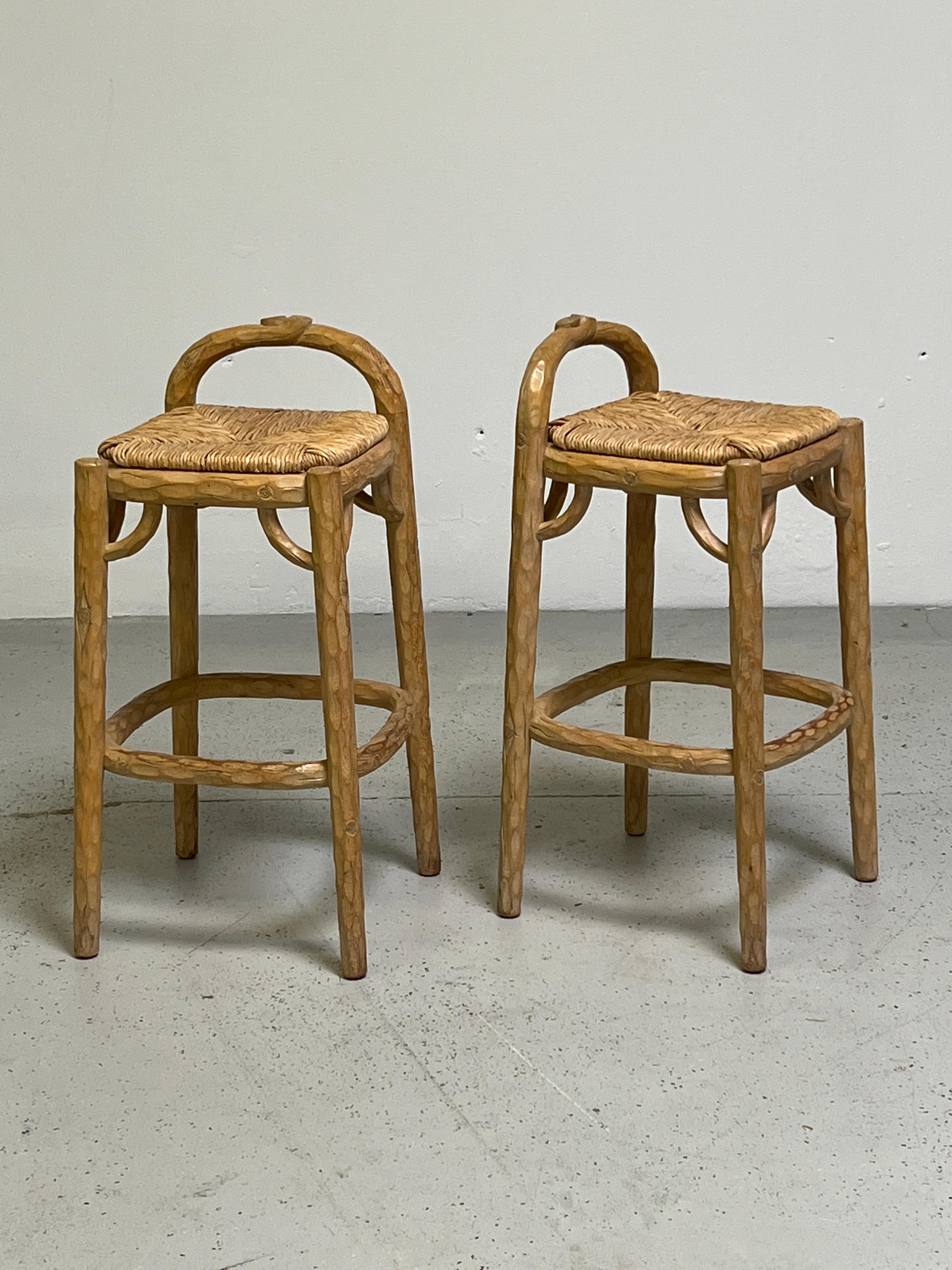 A pair of custom carved and bleached pine 'Tree Trunk' counter stools with rush seats designed by Michael Taylor for Vern and Gloria Jones, Fair Oaks, California, 1985.