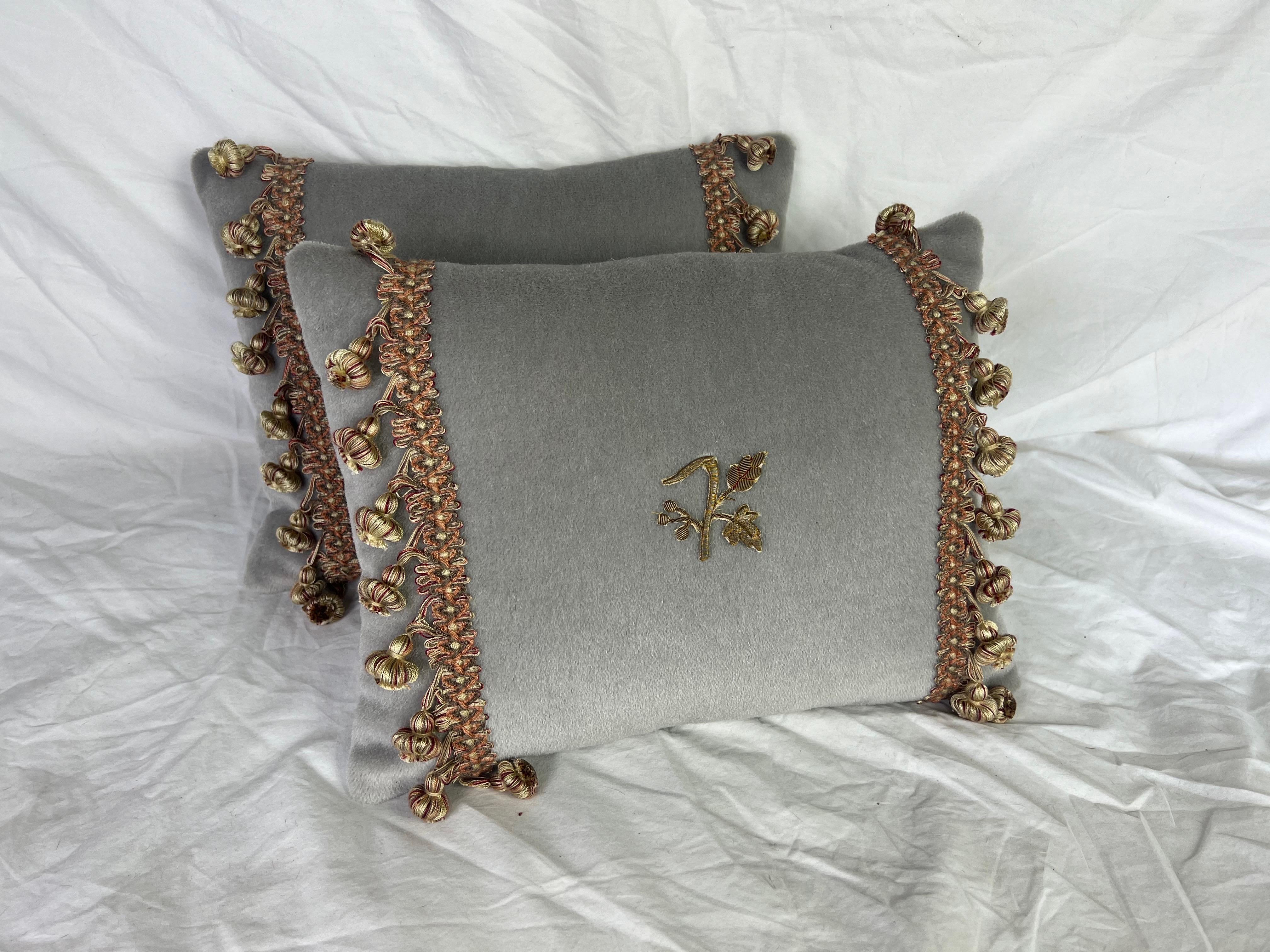 Pair of custom rectangular cushions in a soft, muted gray mohair with coordinating linen backs.  The design includes a small, delicate, gold wheat embroidery in the center of the cushion.  The sides are decorated with an ornate trim made of woven