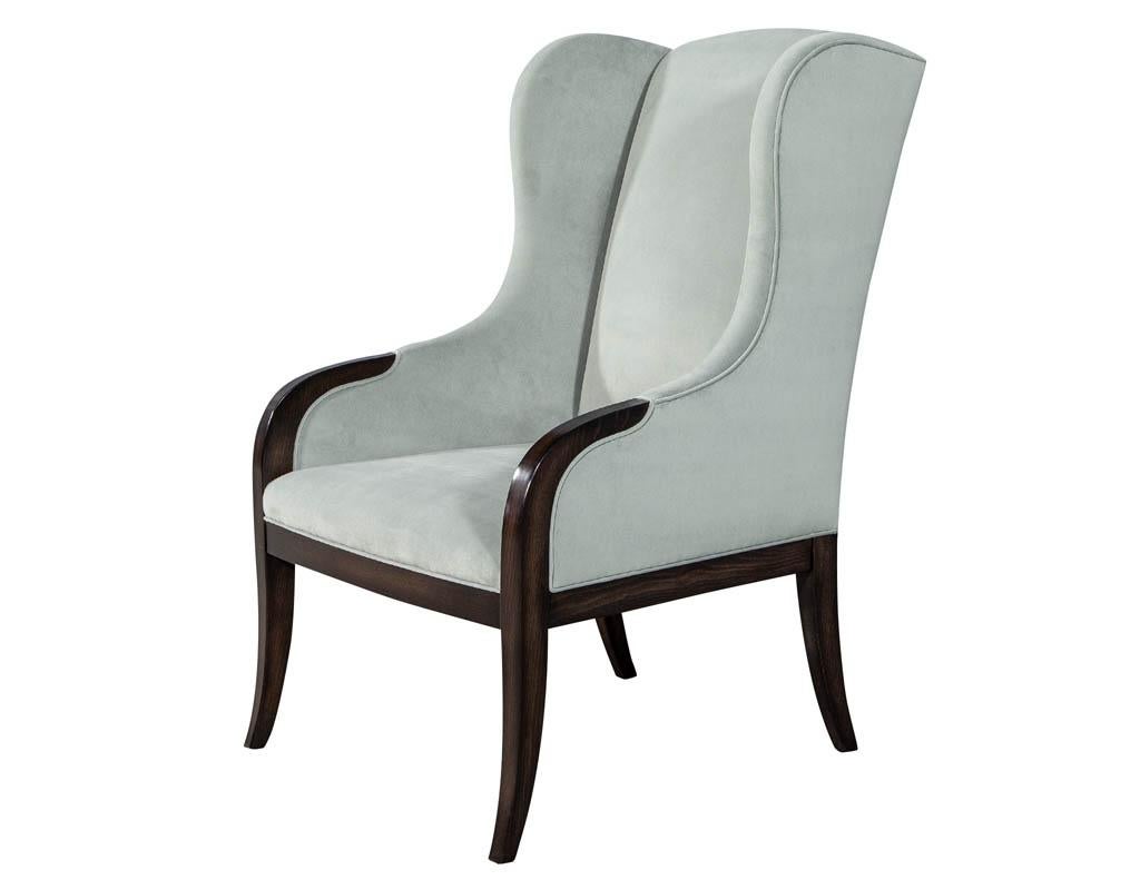 Pair of custom modern wing chairs. These impressive chairs are gracefully curved with a touch of modern meets traditional. Solid European hard wood beechwood frames beautifully hand finished in a rich dark chocolate. Upholstered in a soft silvery