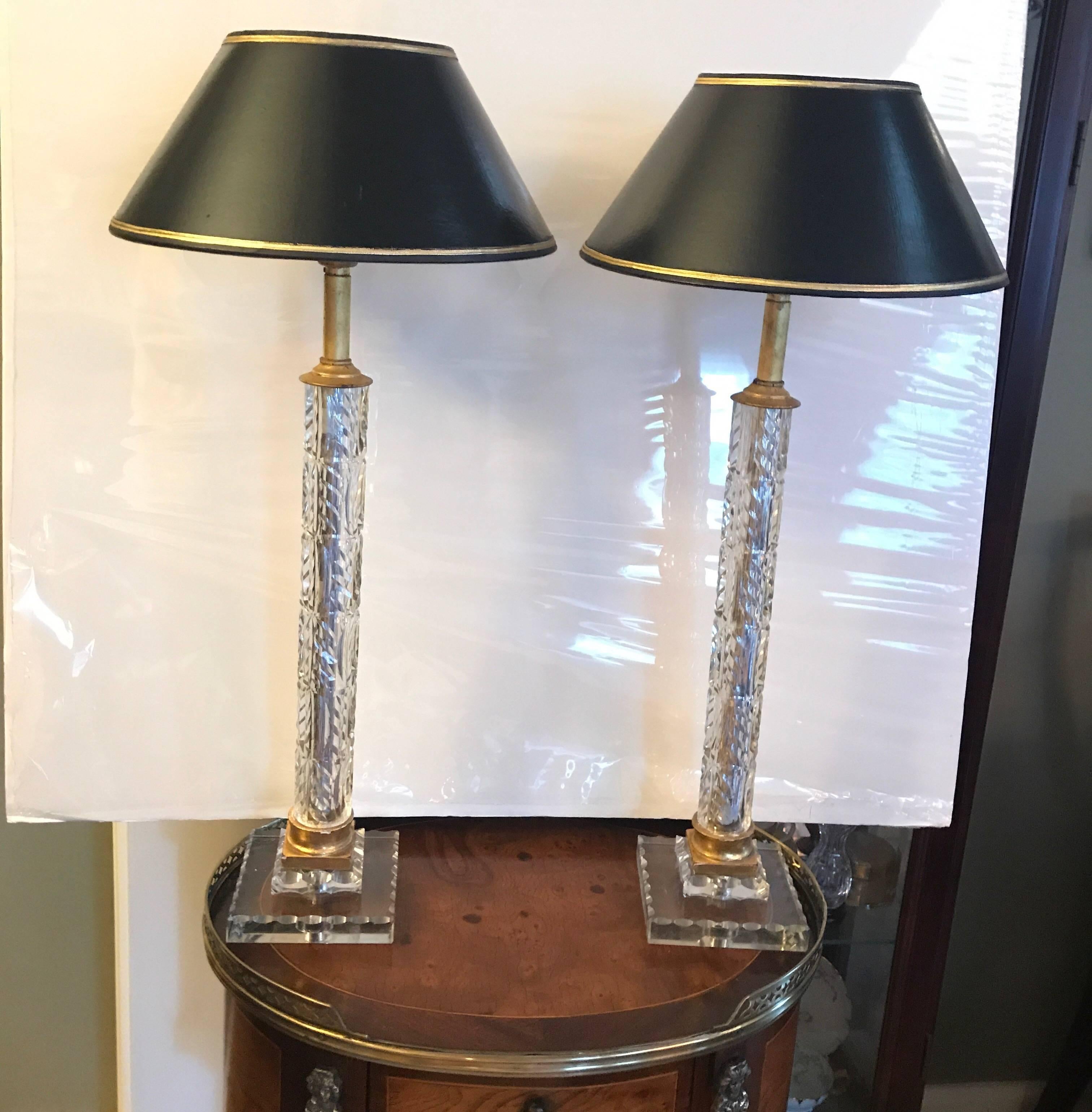 Very chic pair of cut crystal lamps with black parchment shades. The cut centre columns with gilt mounts resting on square double stacked bases. These lamps are one of a kind and were made specially through custom order in the mid-20th century.