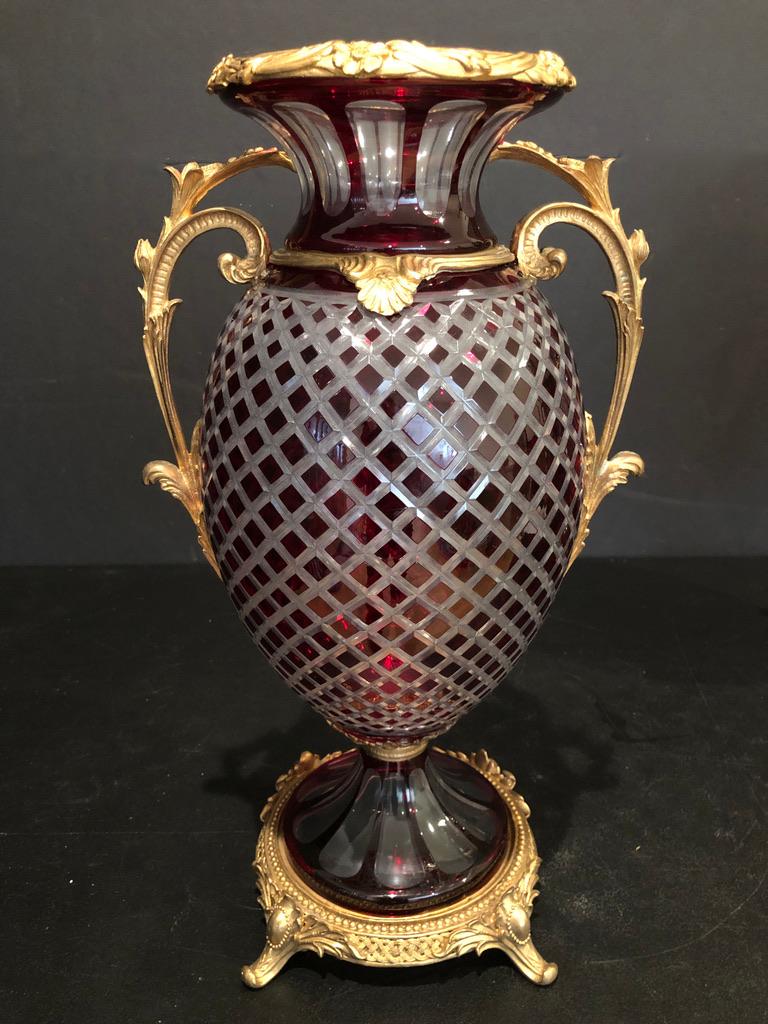 Pair of gilt bronze mounted Baccarat style ruby red cut to clear glass urns. Bulbous form with diamond and facet cut crystal, mounted on gilt bronze footed base with floral form handles.