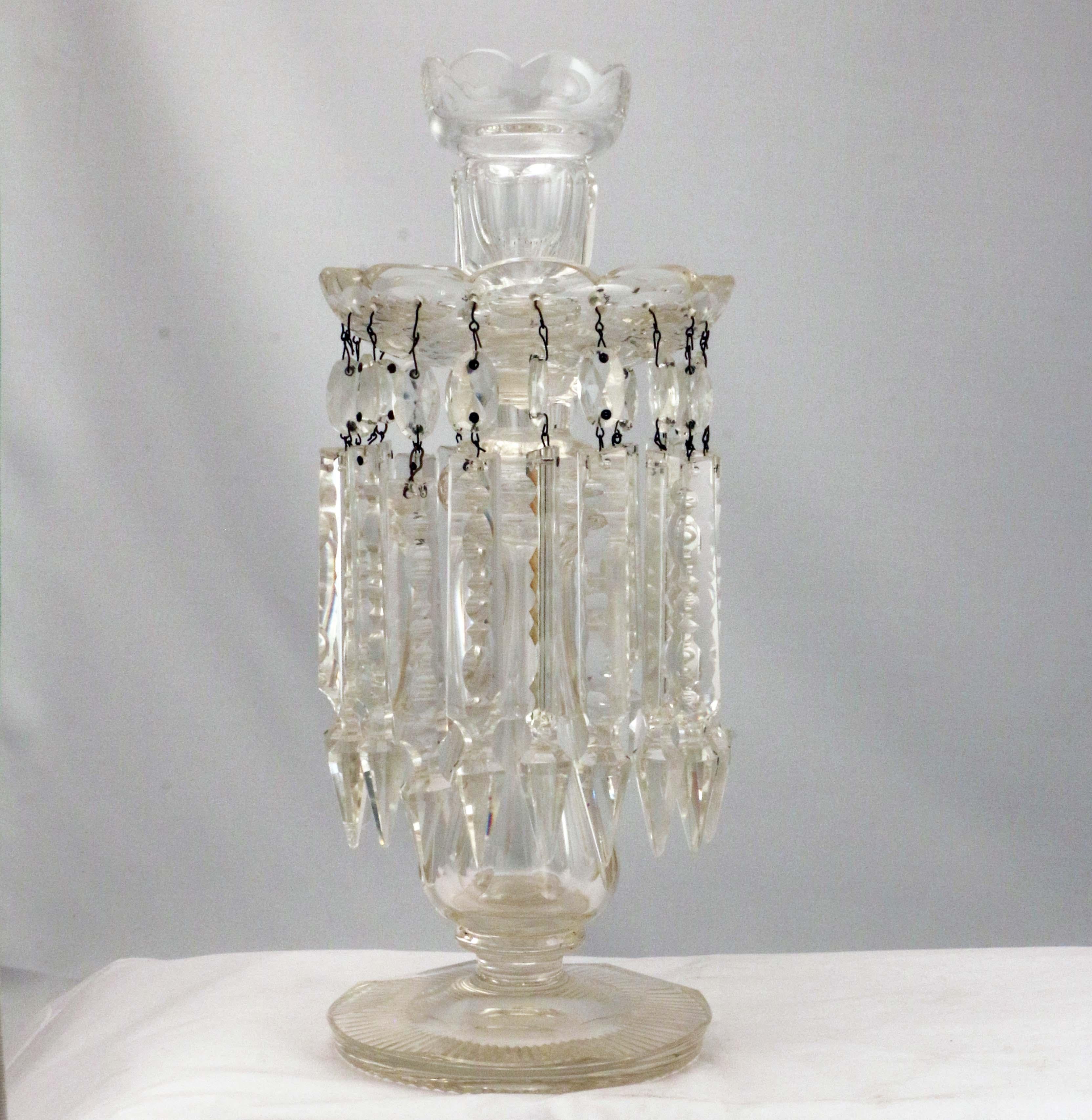 This large pair combine the practicality of the candlestick with the elegance and glitter of the Lustre. The candleholder and drip pan are scalloped, the stem baluster, the base beveled and cut underneath with radiating blazes. The spear-shaped