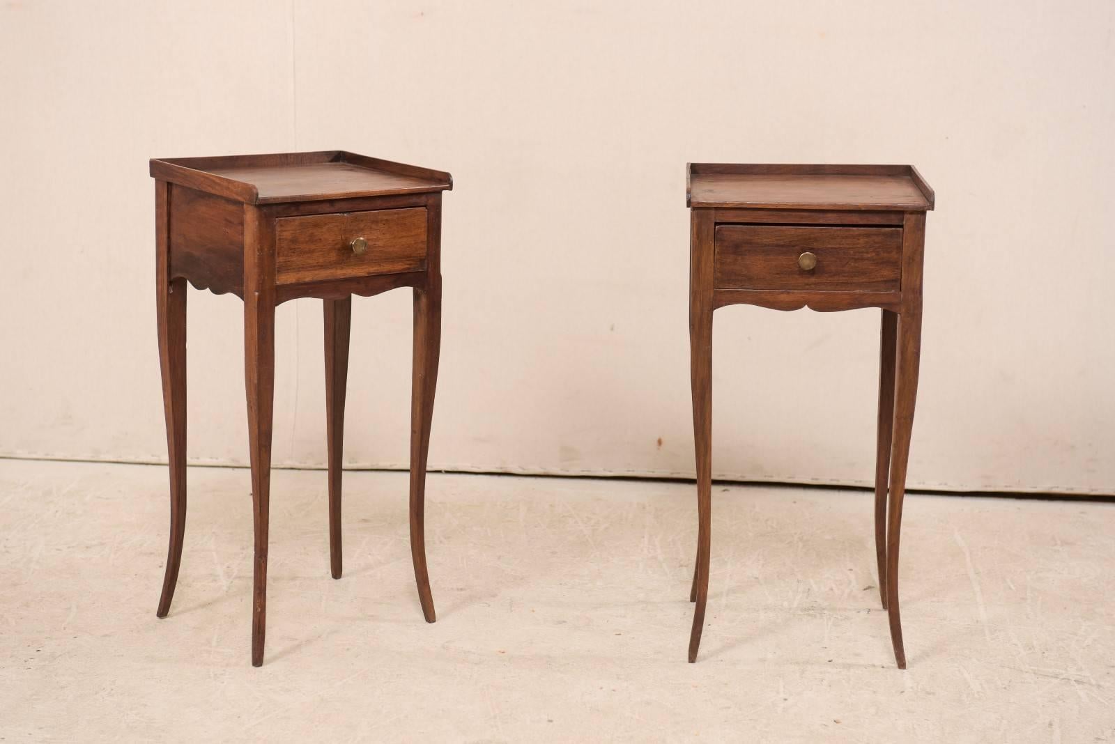 A pair of petite French side tables mid-20th century. This pair of vintage French side tables each features a single drawer, accolade style wavy skirt, and graceful cabriole legs. The top is recessed with a railed edge about three sides (open to the