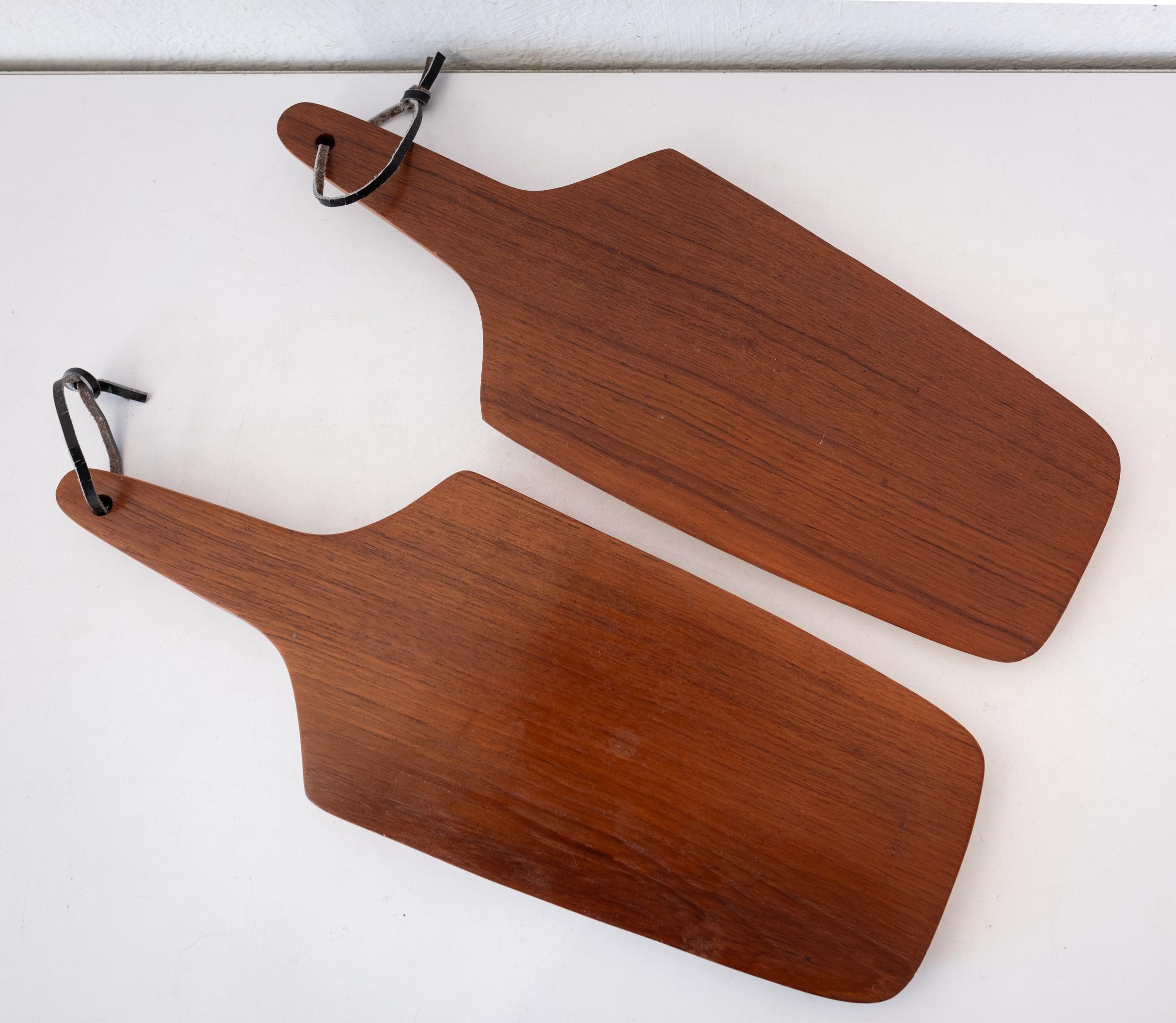 Pair of cutting or charcuterie boards in teak. They both have the original straps for hanging. They appear to be unused. Made in Denmark. 

Each board measures: 15.75x 5.75 x.75 