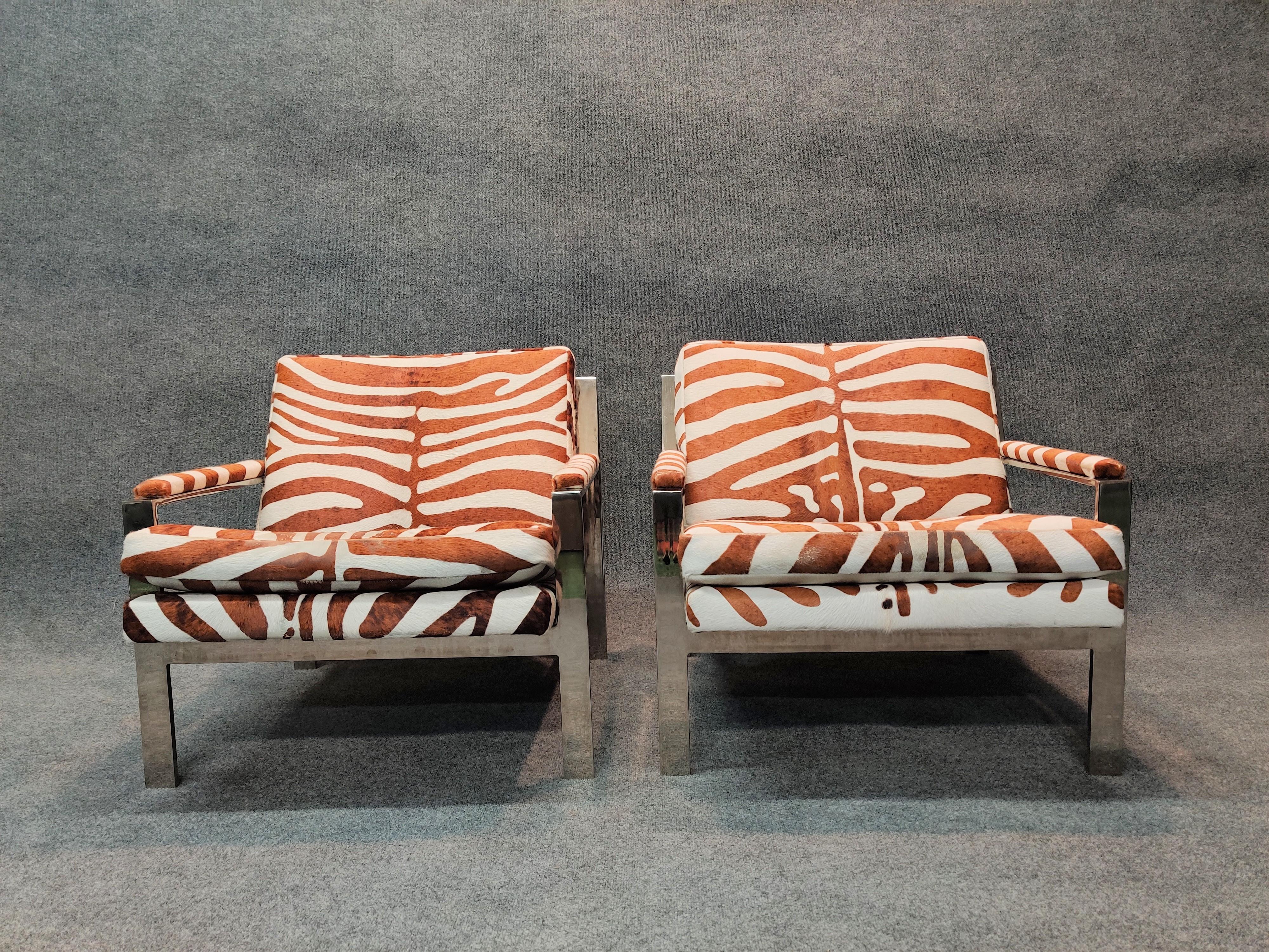 Pair of solid bar steel with chrome finish frames and printed zebra-printed cowhide upholstery, These Cy Mann inspired chairs are classic modern design and will fit in any well appointed interior. Each chair weighs roughly 50 lbs. The finish on the
