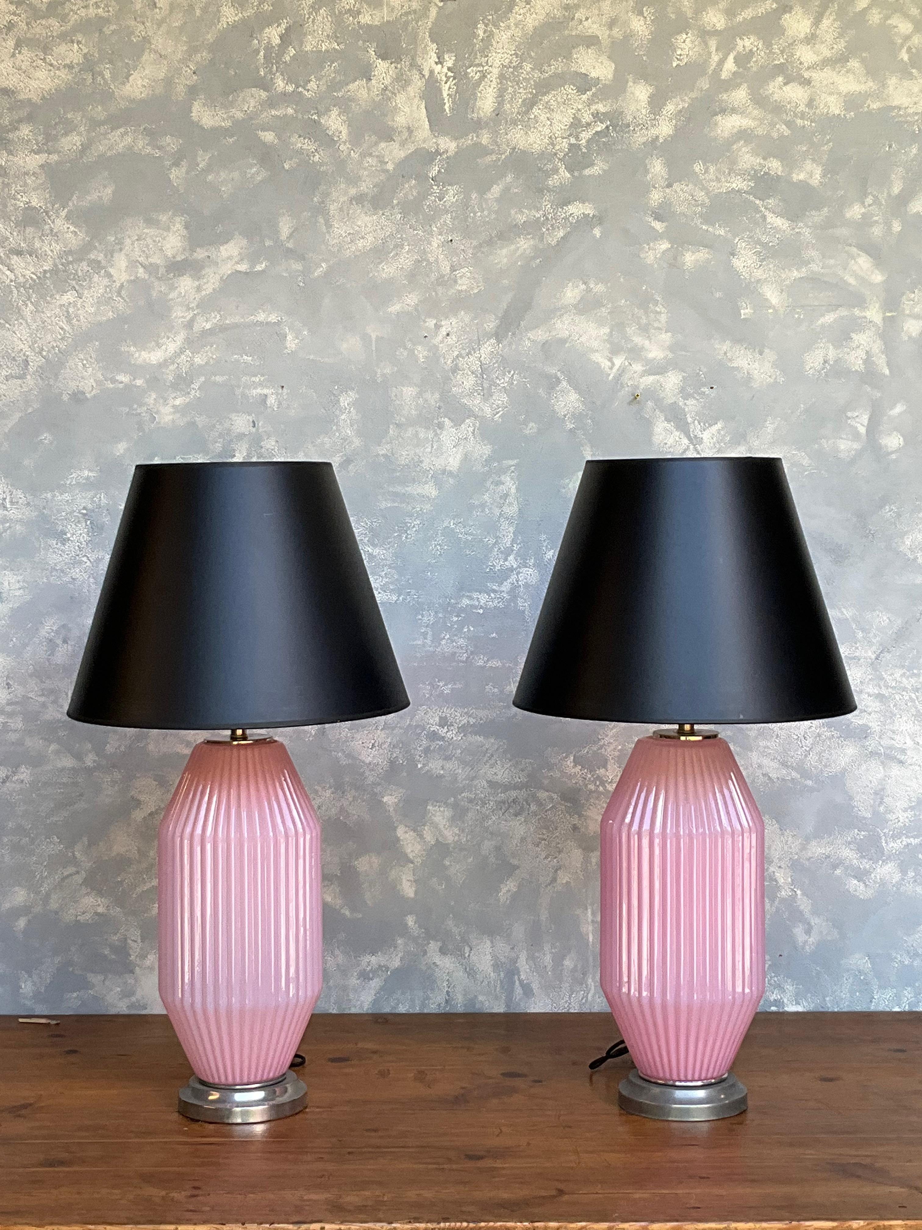 This beautiful pair of Italian 1950s Murano light pink glass lamps possess an enchanting ambiance. Featuring delicate ribbing, these lamps exude elegance and charm. Set on antique nickel bases, they add a touch of vintage sophistication to any