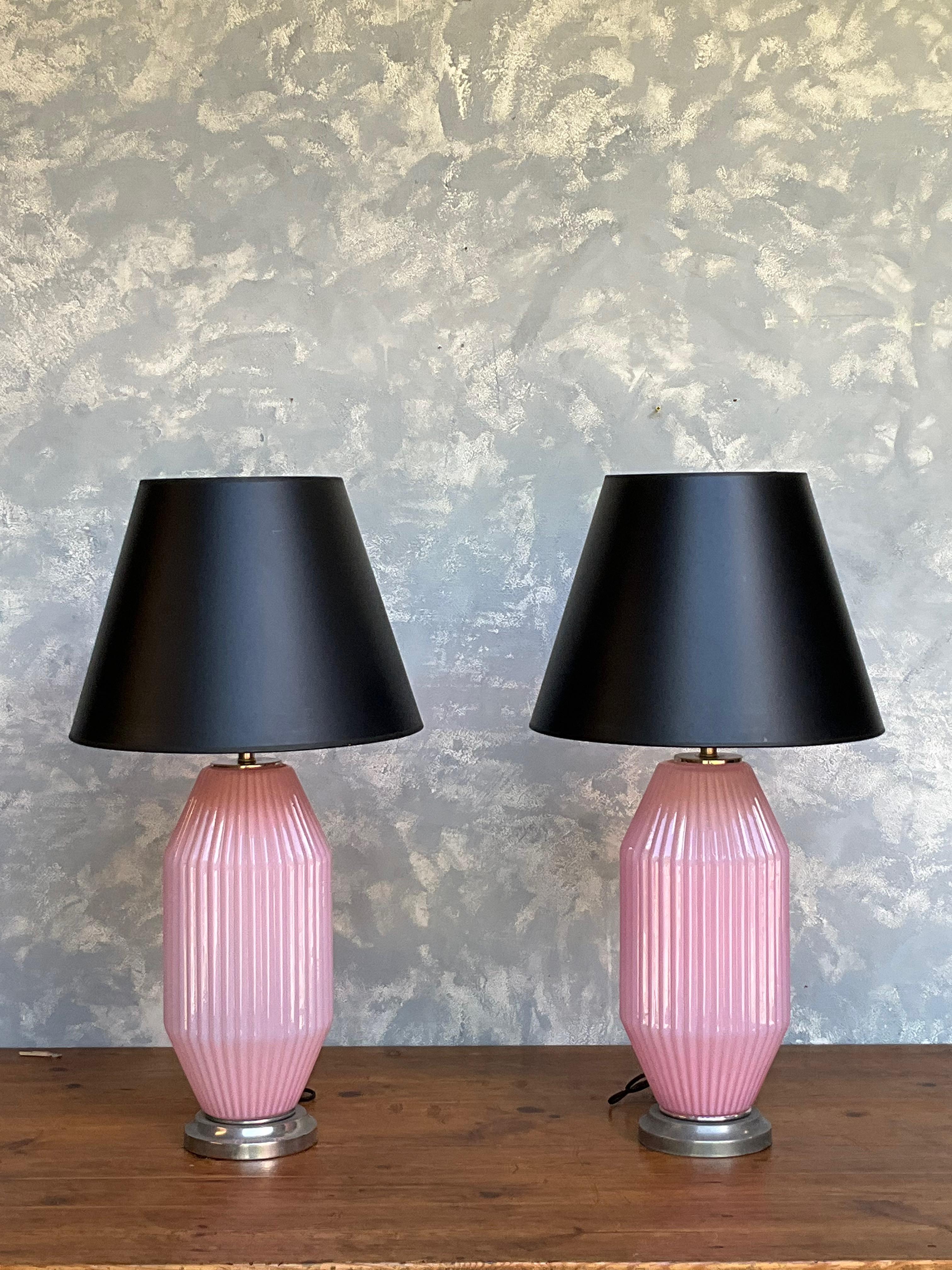 Questa bellissima coppia di lampade in vetro rosa chiaro di Murano degli anni '50 possiede un'atmosfera incantevole. Caratterizzate da delicate nervature, queste lampade emanano eleganza e fascino. Montati su basi in nichel antico, aggiungono un