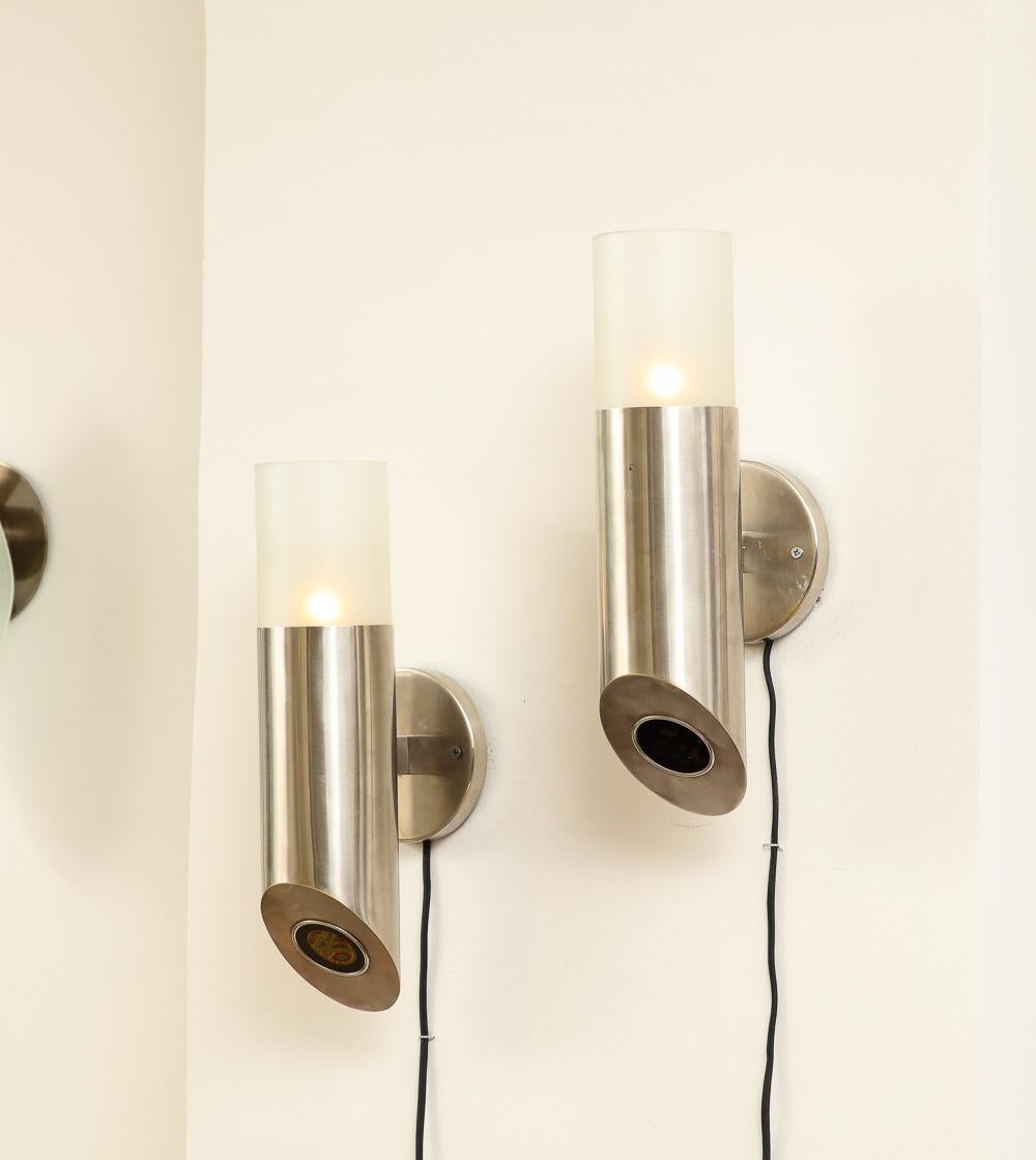 Brushed chrome bases, frosted glass diffuser shades and tinted glass discs. Each sconce has two candelabra sockets. One on the top which illuminates the shade and one at the bottom which illuminates a tinted glass disc. Arredoluce sticker to inside