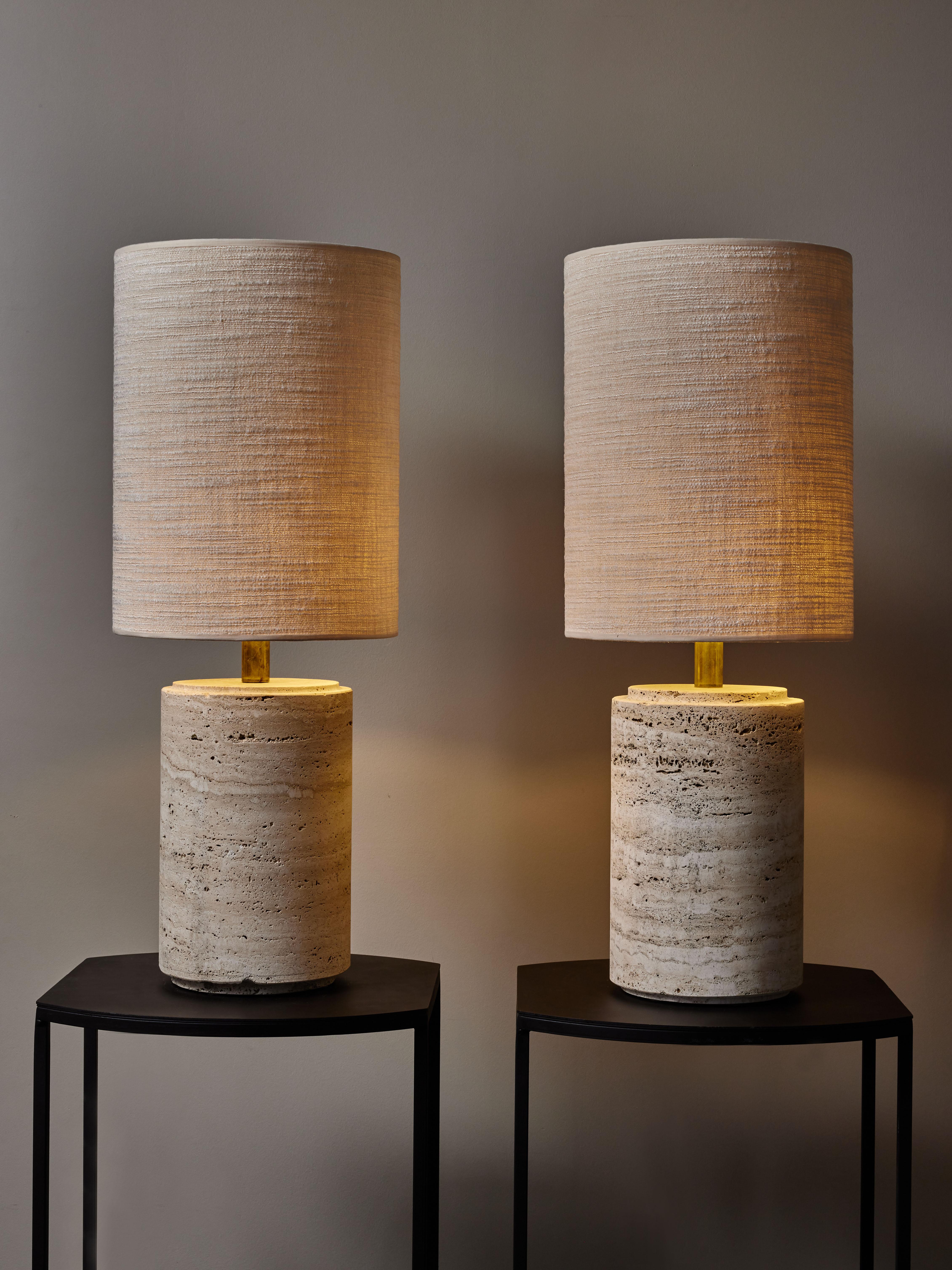 Pair of table lamps made of a travertine cylinder with a brass neck, topped with Dedar fabric lampshade.